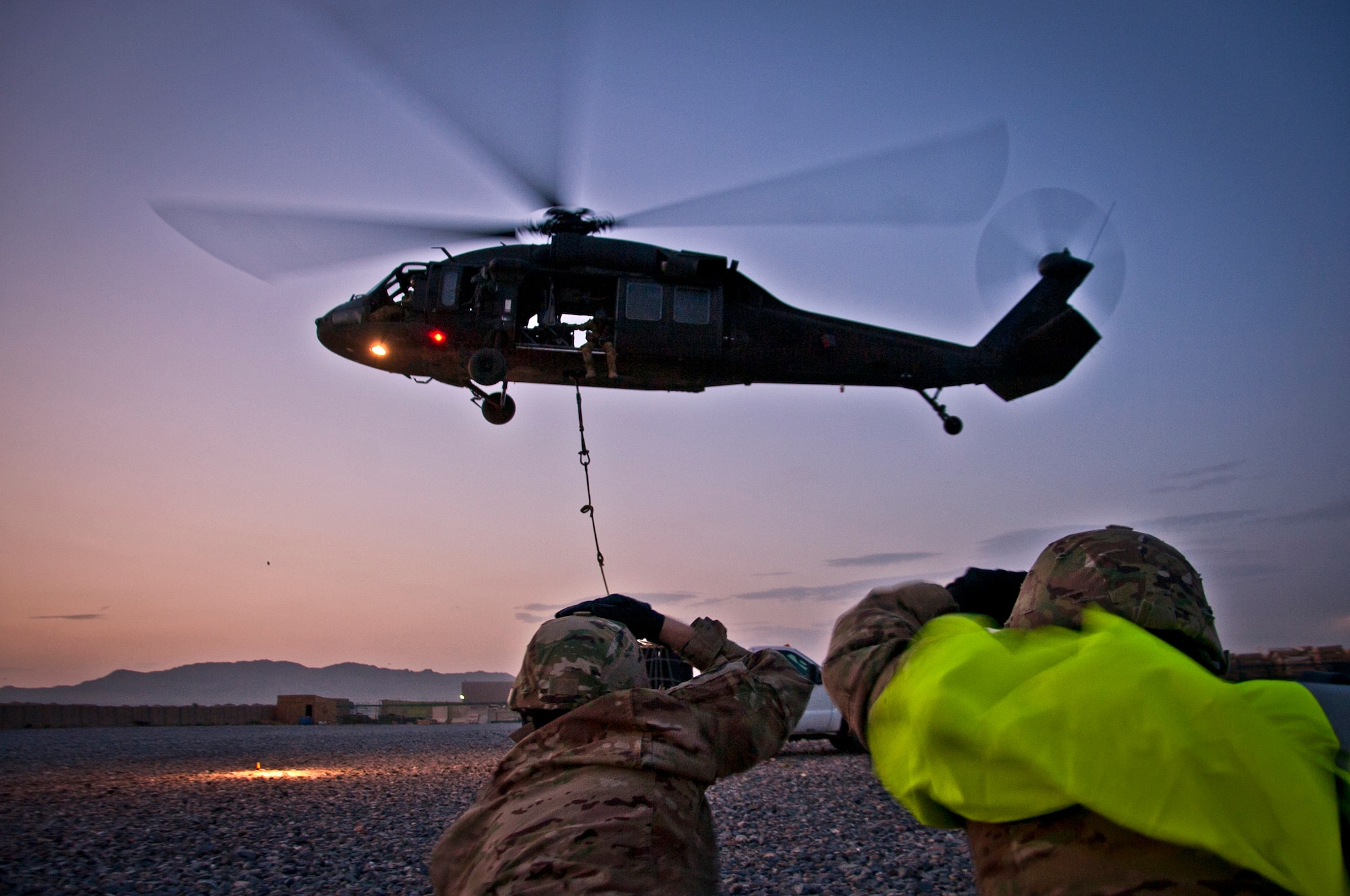 U.S. Air Force Tech. Sgt. Sean Buck and Airman 1st Class Pedro Cahua, both with the 451st Expeditionary Aircraft Maintenance Squadron, signal “all-clear” to the crew of a UH-60 Black Hawk helicopter after sling-loading a 1,800 pound A-22 cargo bag during a joint-coalition training mission at Kandahar Airfield, Afghanistan, June 1, 2013. The aircrew consisted of Soldiers from the 3rd Combat Aviation Brigade here. The training provided coalition members the opportunity to learn the concepts of illuminating a landing zone as well as in-flight cargo sling loading. (U.S. Air Force photo/Senior Airman Scott Saldukas)
