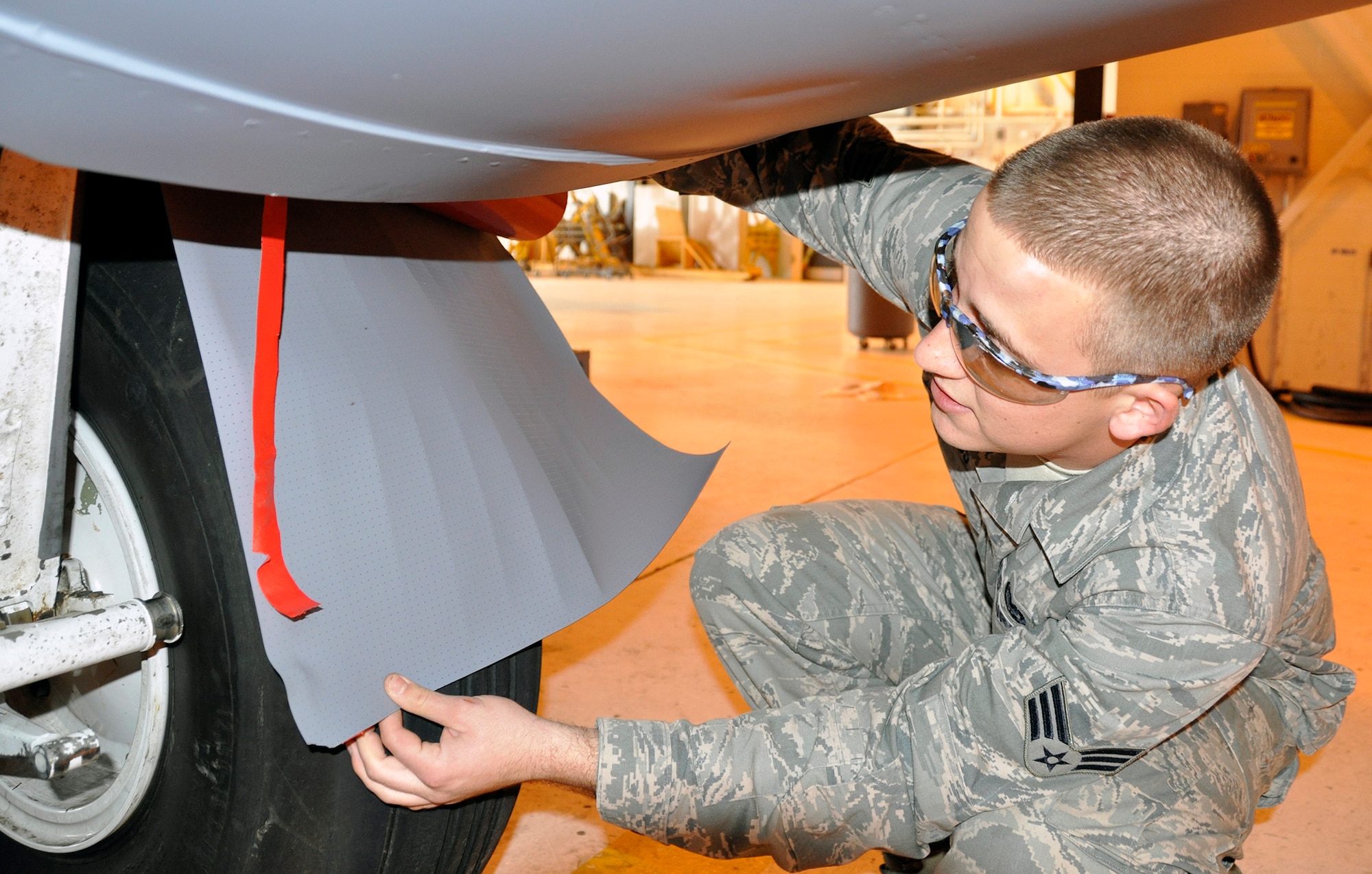 Air Force Reserve Senior Airman Joseph Jennings demonstrates how industrial tape is used to protect the C-130’s forward landing gear struts. The 302nd Maintenance Group uses the tape to extend the life of the struts. Jennings is an Aircraft Structural Apprentice with the 302nd Maintenance Squadron. (U.S. Air Force photo/Master Sgt. Daniel Butterfield)