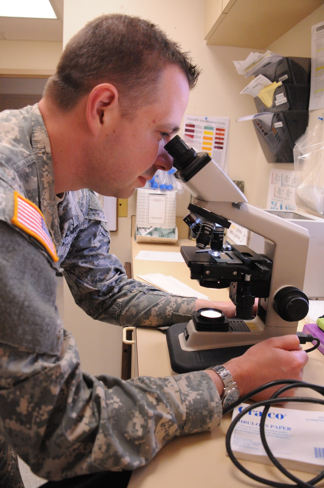 Army Capt. David Rowland, veterinarian, looks at a blood sample through a microscope at the Kirtland veterinary clinic. Rowland will be leaving the clinic in July, forcing a temporary reduction in clinic services.