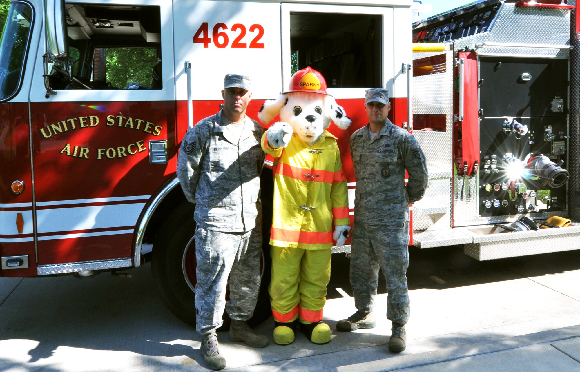 Tech. Sgt. Matthew Reinhardt and Staff Sgt. Steven Short, fire inspectors from the 375th Civil Engineer Squadron, stand around Sparky the Dog in front of a fire truck at Fire Station One, May 29, 2013. The Fire Department wishes to emphasize the importance of wildfire prevention on and off-base. (U.S. Air Force Photo by Airman Megan Friedl)
