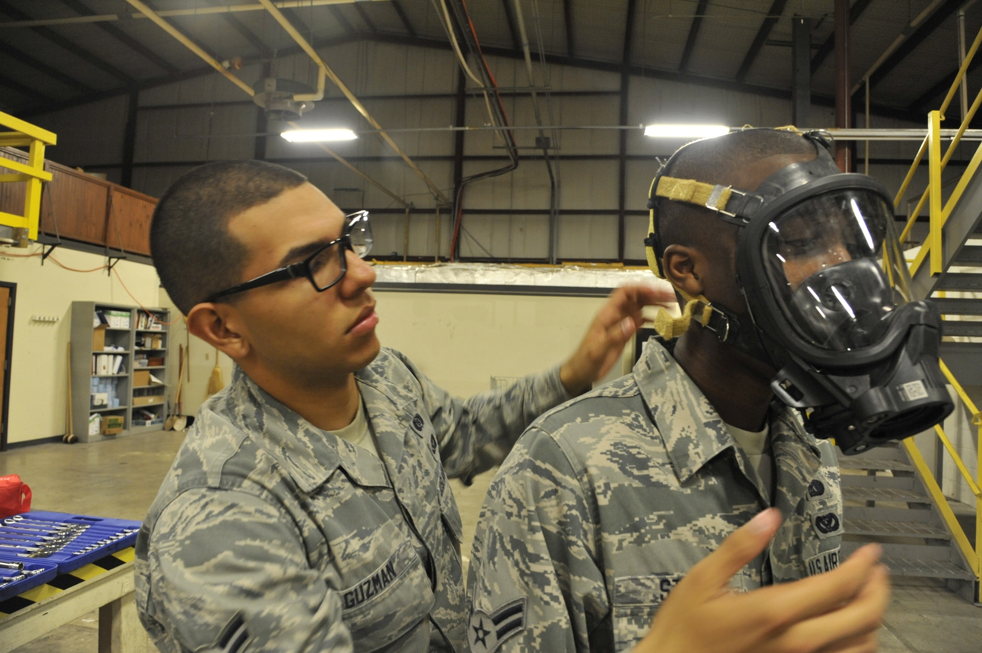 Airman 1st Class Alfredo Guzman, 509th Civil Engineer Squadron journeyman, assists Airman 1st Class Brandon Stone, 509th CES apprentice, with donning a FireHawk M7 mask at Whiteman Air Force Base, Mo., May 22, 2013. The mask is a self-contained breathing apparatus used to prevent any inhalation of chemicals or biological hazards. (U.S. Air Force photo by Airman 1st Class Keenan Berry/Released)
