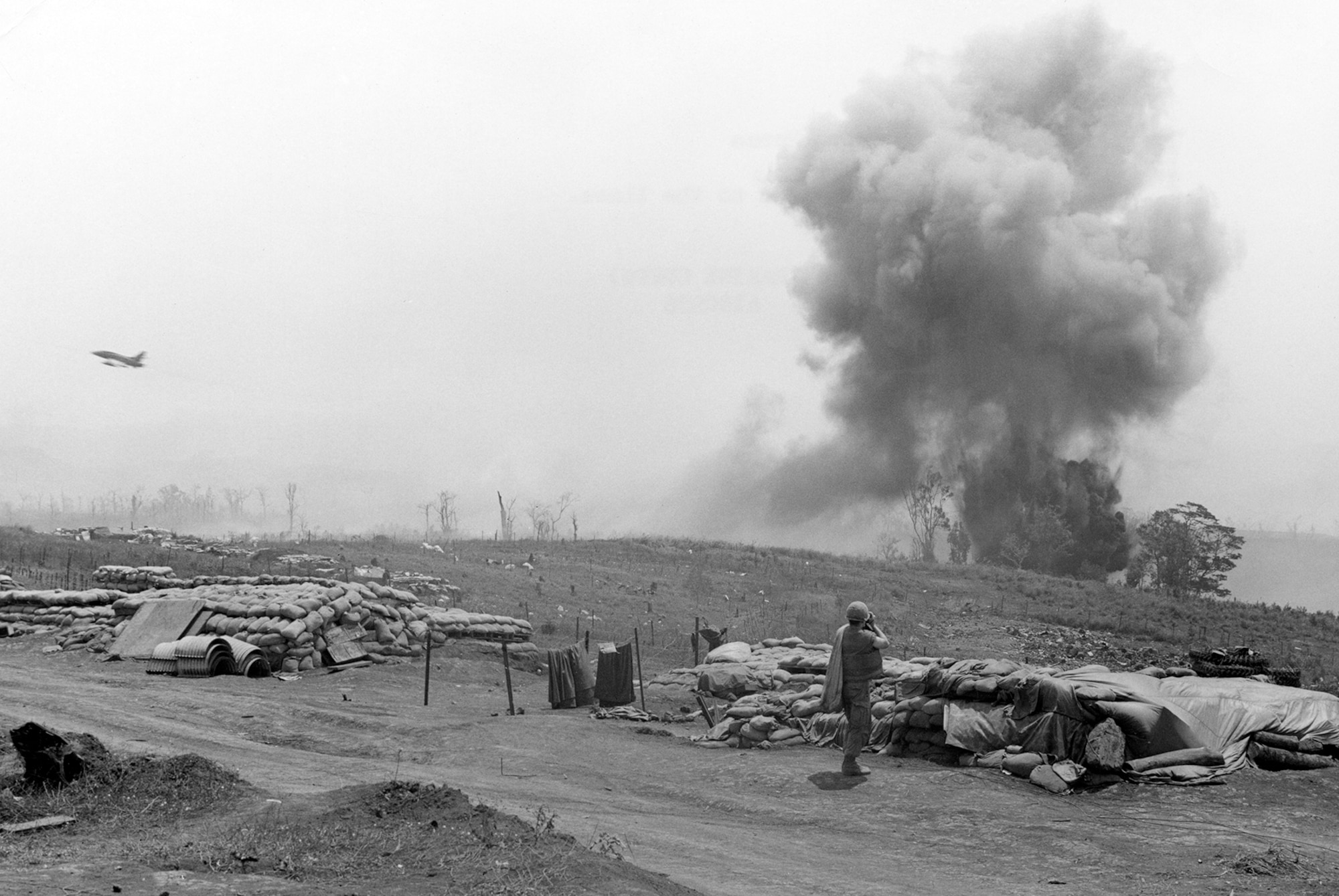 A U.S. Marine photographer is shown taking a photo of a USAF F-100 accurately delivering its bombs just a few yards outside the perimeter wire at Khe Sanh on March 15, 1968. (U.S. Air Force photo)