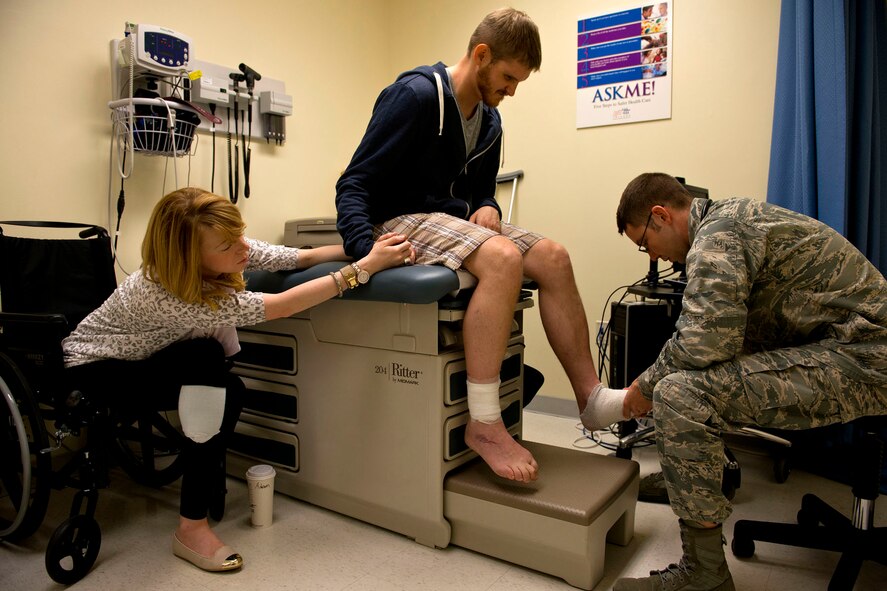 HANSCOM AIR FORCE BASE, Mass. -- Lieutenant Justin Farmer, a physician assistant at the 66th Medical Squadron, conducts a follow up examination with Capt. Adam Davis, joined by his wife Adrianne, to check the progress of his healing. (U.S. Air Force photo/Tech. Sgt. Bennie J. Davis III)