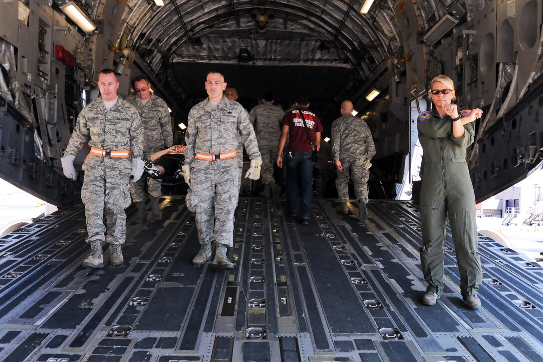 Air Force Capt. Tammy Ostrowski directs airmen carrying a simulated patients inside the cargo bay of a C-17 Globemaster III transport aircraft to a triage area by emergency services personnel during Golden Eagle III on Stewart Air National Guard Base, N.Y. June 1, 2013. Ostrowski is assigned to the New York Air National Guard's 139th Aeromedical Evacuation Squadron.