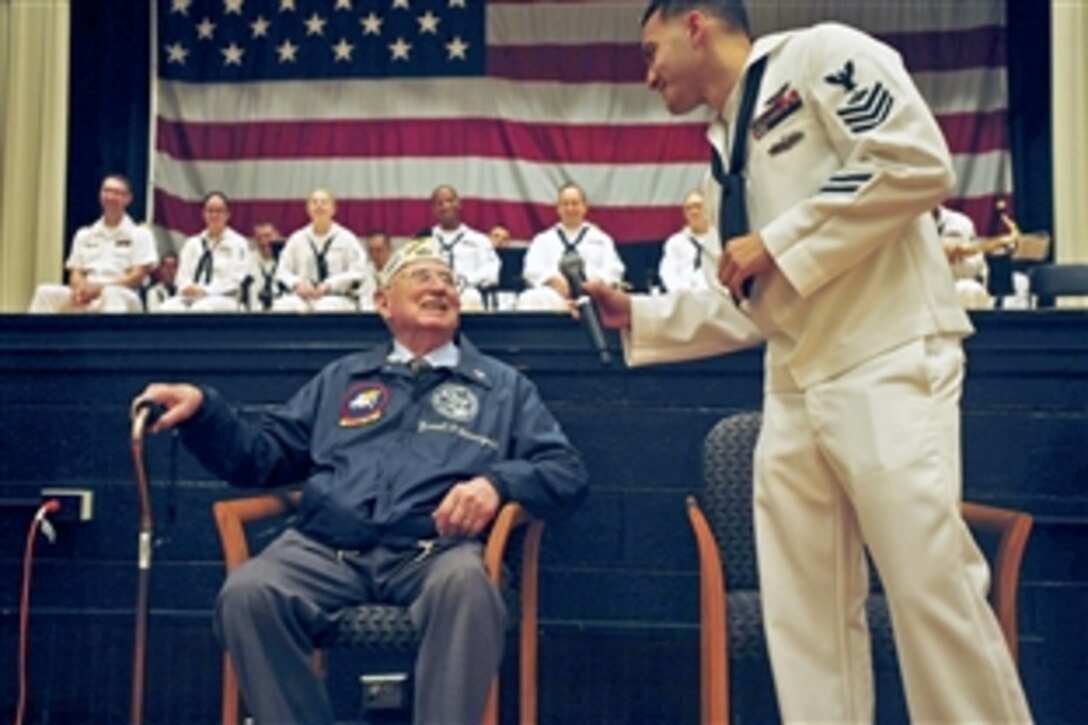 Navy Capt. David A. Culler, right, holds a microphone for retired Navy Chief Petty Officer Earnest "Dave" Davenport as he shares his recollection of the Battle of Midway during a ceremony to commemorate the battle's 71st anniversary on Naval Station Norfolk, June 5, 2013. Davenport served as an aviation machinist's mate and enlisted pilot, and worked 60 hours during the battle. Culler is the naval station's commanding officer.