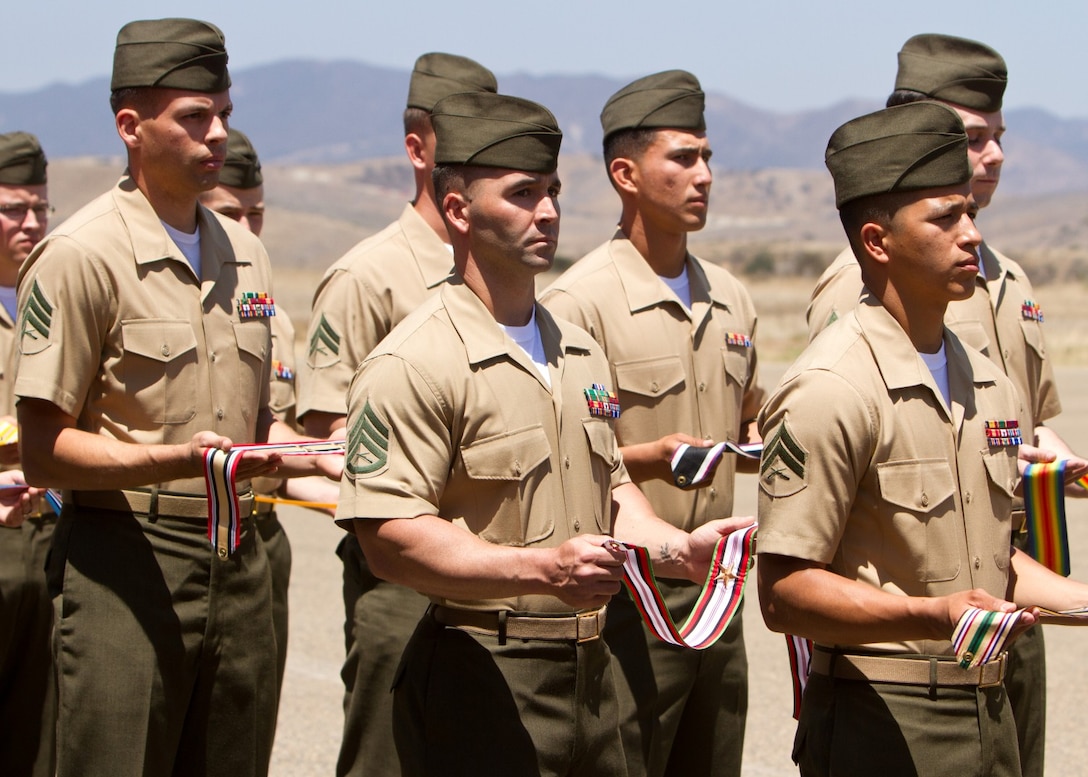 Staff Sgt. Ryan Sotelo, a platoon sergeant serving with Weapons Company, 3rd Battalion, 5th Marine Regiment, holds the Afghanistan Campaign Streamer during a battle colors rededication ceremony at the Camp San Mateo helicopter landing pad here, June 5, 2013. Marines serving with 5th Marine Regiment, 1st Marine Division, added the Afghanistan Campaign streamer and rededicated streamers from previous campaigns to the regiment's battle colors during the ceremony. The Fighting Fifth is recognized as the most decorated regiment in the Marine Corps. Marines and sailors of the regiment earned the Afghanistan Campaign streamer during a yearlong deployment to Afghanistan as Regimental Combat Team 5 from August 2011 to August 2012. Sotelo, a San Mateo, Calif., native, is a Silver Star recipient and a combat veteran of Operation Enduring Freedom.