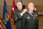 Maj. Gen. Raymond F. Rees, the adjutant general of the Oregon National Guard, places an Oregon Distinguished Service Medal around the neck of Chief Warrant Officer 5 James Powell at his retirement ceremony Nov. 3 at the Anderson Readiness Center in Salem, Ore. Powell recieved the award in recognition of his 39 years of military service.