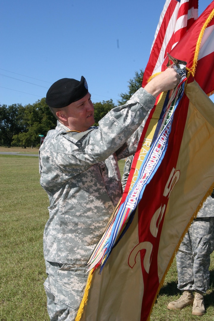 Col. Tom Blackstock, commander of the 265th Regional Support Group, pins the streamer for the Navy Presidential Unit Award to the unit's guide-on. The Metter, Ga. based unit became the only unit in Georgia Army National Guard history to be awarded a Navy Presidential Unit Citation during a ceremony Nov. 1 at the Metter Armory.