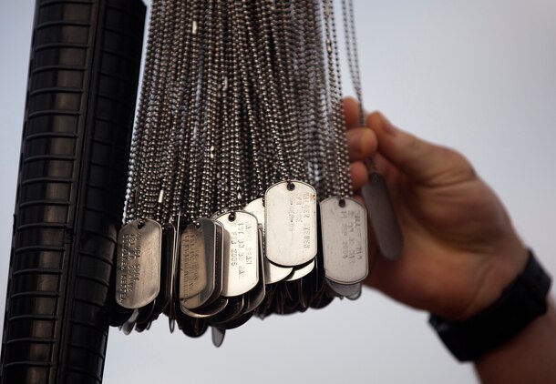 MARINE CORPS BASE HAWAII - A Marine from 3rd Battalion, 3rd Marine Regiment slides his hand down a pair of dog tags as he hangs them upon the pedestal on Marine Corps Base Hawaii, June 06. A total of 119 Marines and sailors who hung dog tags of fallen heroes wore black shirts that read, “All gave some. Some gave all. In memory of our fallen brothers.” (U.S. Marine Corps photo by Lance Cpl. Matthew Bragg)