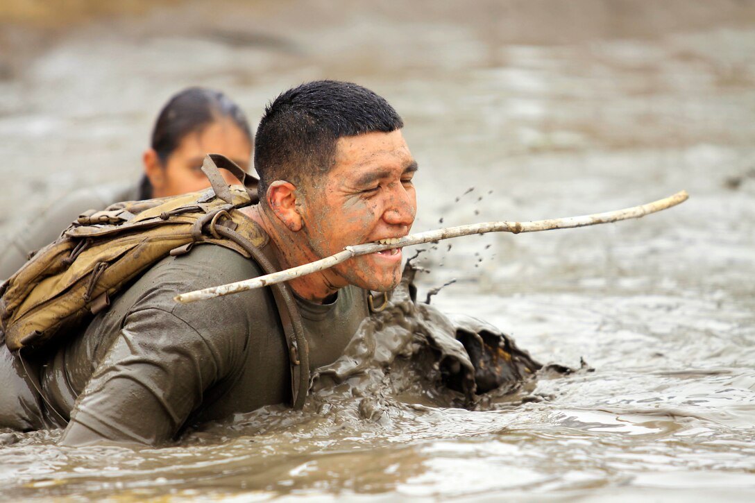 Staff Sgt. Daniel Soto, with Combat Logistics Battalion here, pulls a stick out of the last mud pit with his teeth as he approached the finish line to prevent injury to other runners during the Wold Famous Mud Run here Jun 7. 