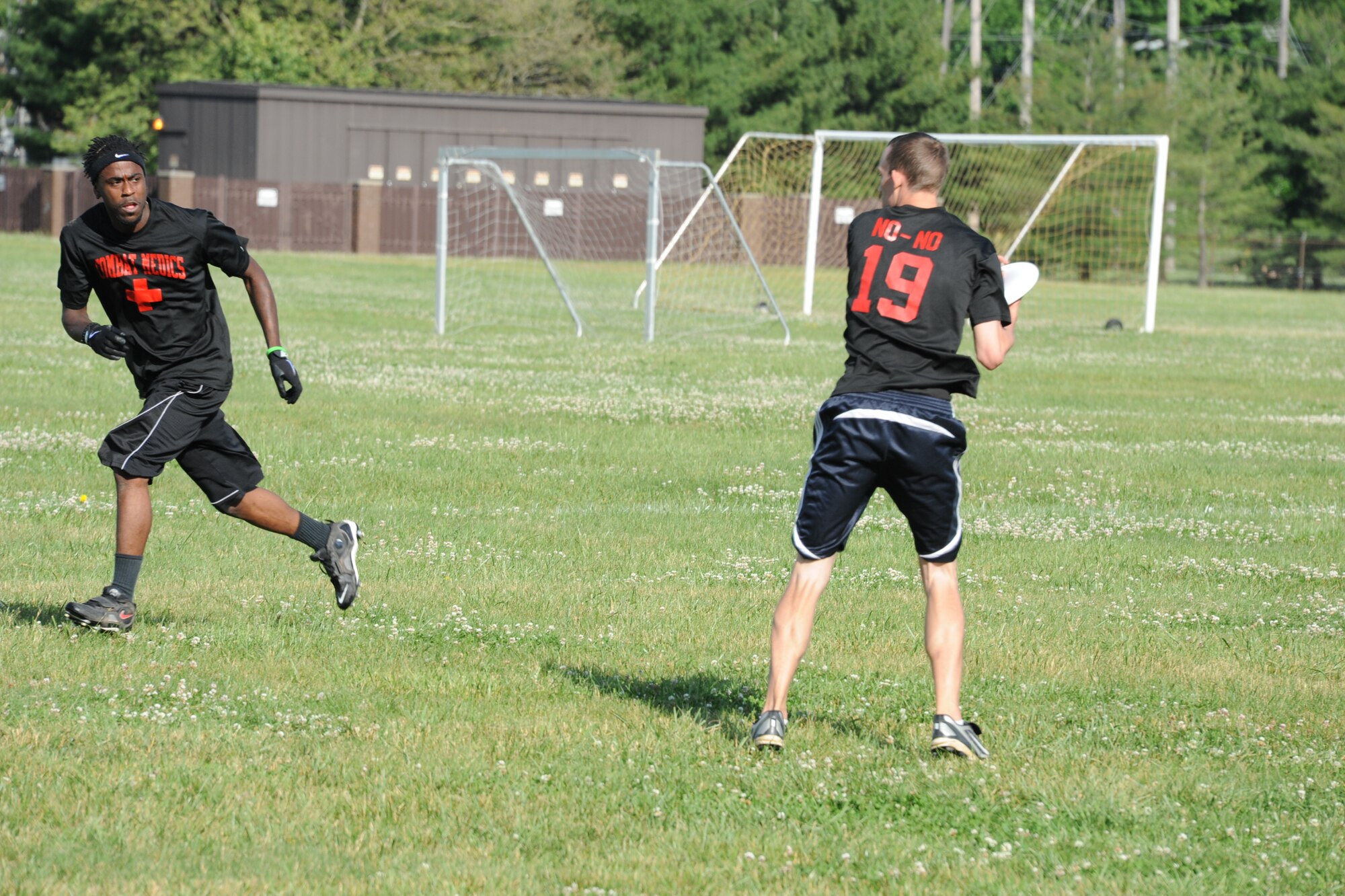 Airman 1st Class Ronald Mapper, 87th Medical Group aerospace medical technician, passes off a flying disc to Terrance Salter, 87th MDG logistics specialist, during an ultimate flying disc game June 5, 2013, at Joint Base McGuire-Dix-Lakehurst, N.J. Salter caught the flying disc and threw a pass to gain a point for his team, making the score 5-4. Mapper is a Detroit native and Salter hails Tampa, Fla. (U.S. Air Force photo by Airman Sean M. Crowe/Released)