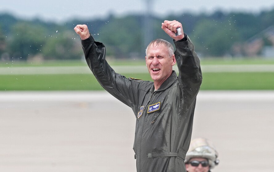 Col. David Almand, 375th Air Mobility Wing commander, cheers after being sprayed with a fire hose following his fini-flight as wing commander at Scott Air Force Base, Ill. June 6, 2013. A commander's fini-flight is an Air Force tradition meant to honor and thank the commander for his service. Almand will relinquish his command of the 375th at a change of command ceremony 14 June, 2013.(U.S. Air Force photo/ Staff Sgt. Ryan Crane)