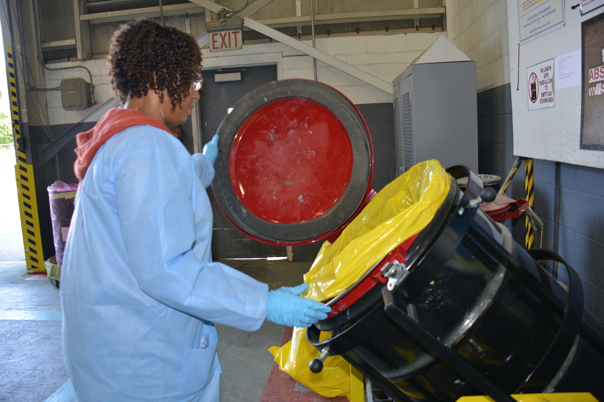Carla Hodges, Hazardous Waste Disposer, demonstrates the new trash can stand that prevents back injuries. The Ergonomics Office here designed and developed the new device. (U.S. Air Force photo by Ed Aspera/Released)