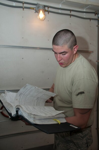 Airman 1st Class Jacob Gaytan, 90th Missile Maintenance Squadron missile maintenance technician, reads technical orders for his task of stabilizing a payload transport above a launch tube in preparation for removing aerospace vehicle equipment June 3 at the Uniform-01 training site. Gaytan, along with Airman 1st Class Anthony Deprizio, also a 90th MMX/MMT, formed the topside crew of the operation. (U.S. Air Force photo by Airman 1st Class Jason Wiese)