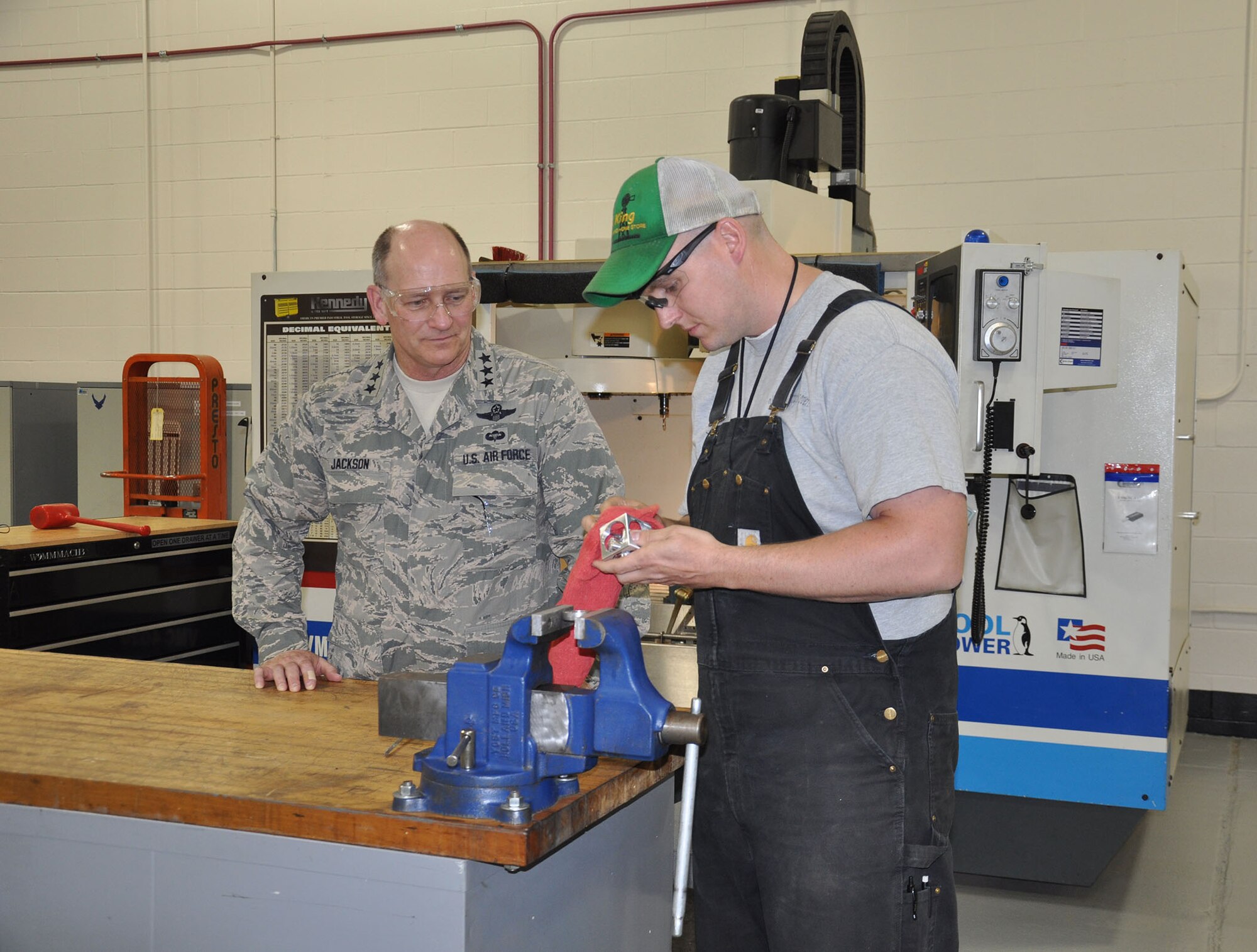 WRIGHT-PATTERSON AIR FORCE BASE, Ohio –Staff Sgt. Michael Foster, 445th Maintenance Squadron aircraft metals technician, demonstrates to Lt. Gen. James F. Jackson, commander, Air Force Reserve Command, the versatility of the Computer Numerical Control machine (in the background) for the production of non-procurable aircraft components and support equipment during the general’s visit to the 445th Airlift Wing June 6, 2013. (U.S. Air Force photo/Stacy Vaughn)