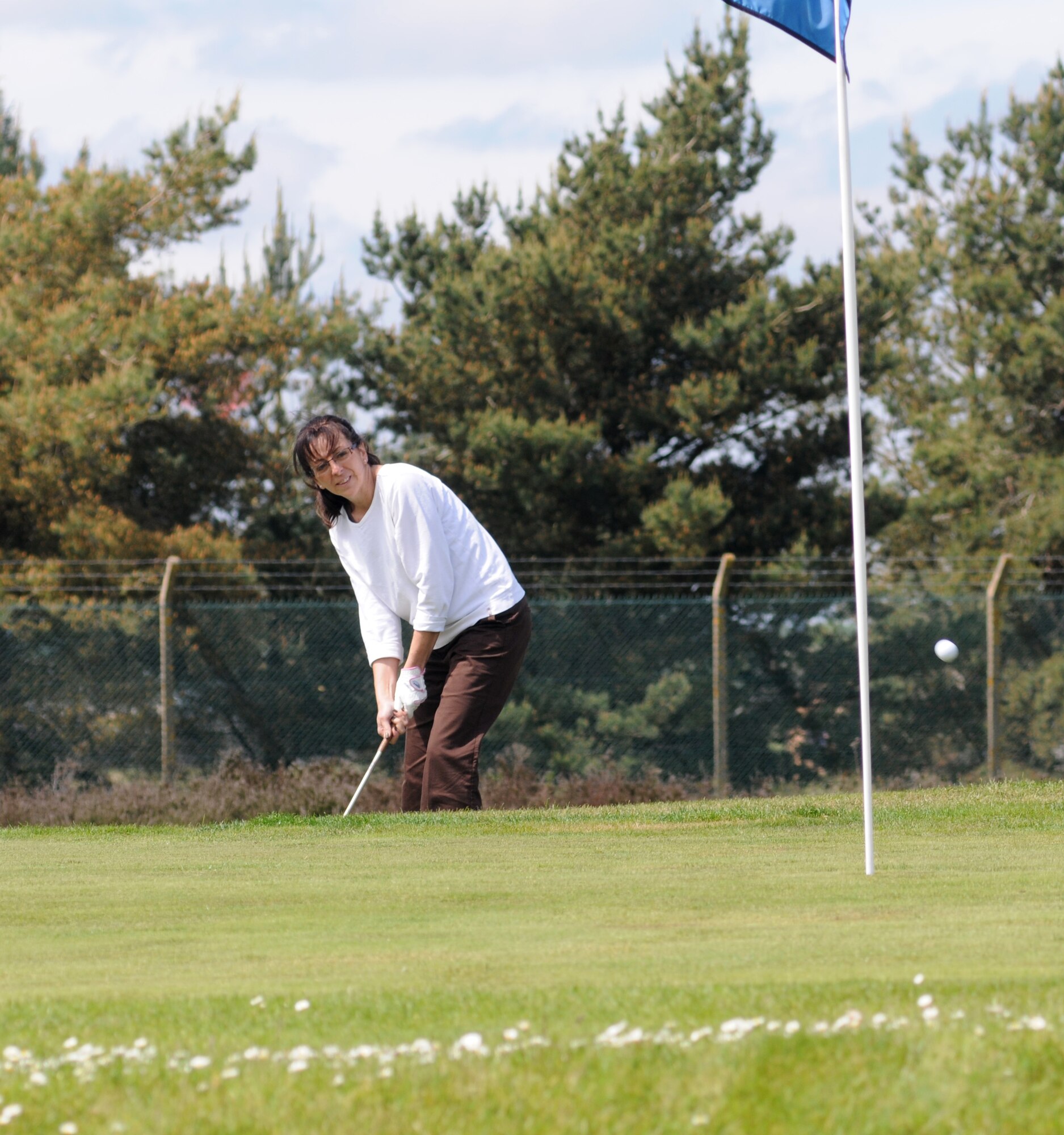 Janet Evans, 100th Force Support Squadron Child Development Center director from Manchester, N.H., chips onto the 11th green during intramural golf June 5, 2013, at the Breckland Pines Golf Club on RAF Lakenheath, England. Breckland Pines is a nine-hole heathland type course with 18 different tee positions. (U.S. Air Force photo by Gary Rogers/Released)
