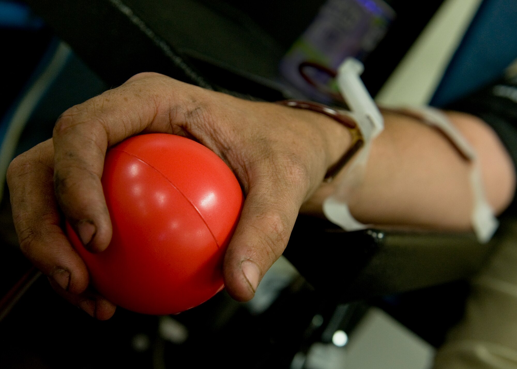Airman 1st Class Rudy McDade, 7th Aircraft Maintenance Squadron, grips a stress ball to increase blood flow during his donation June 5, 2013, at Dyess Air Force Base, Texas. McDade donated a double portion of red blood cells during a blood drive hosted by the 7th AMXS and Meek Blood Center. Nearly 1,000 pounds of clothing was also collected at the event and Airman wrote on banners, which will be delivered to victims in areas of Oklahoma most affected by recent natural disasters.  The event gathered nearly 1,000 pounds of clothing and had more than 45 registered blood donors who gave both whole blood and double red blood cells. This is the second year the squadron has hosted a blood drive with hopes of making it a bi-annual event. The blood collected will be distributed to where it is needed most by the Red Cross. The Meek Blood Center will be returning to Dyess July 17, 2013. (U.S. Air Force photo by Airman 1st Class Peter Thompson/Released)
