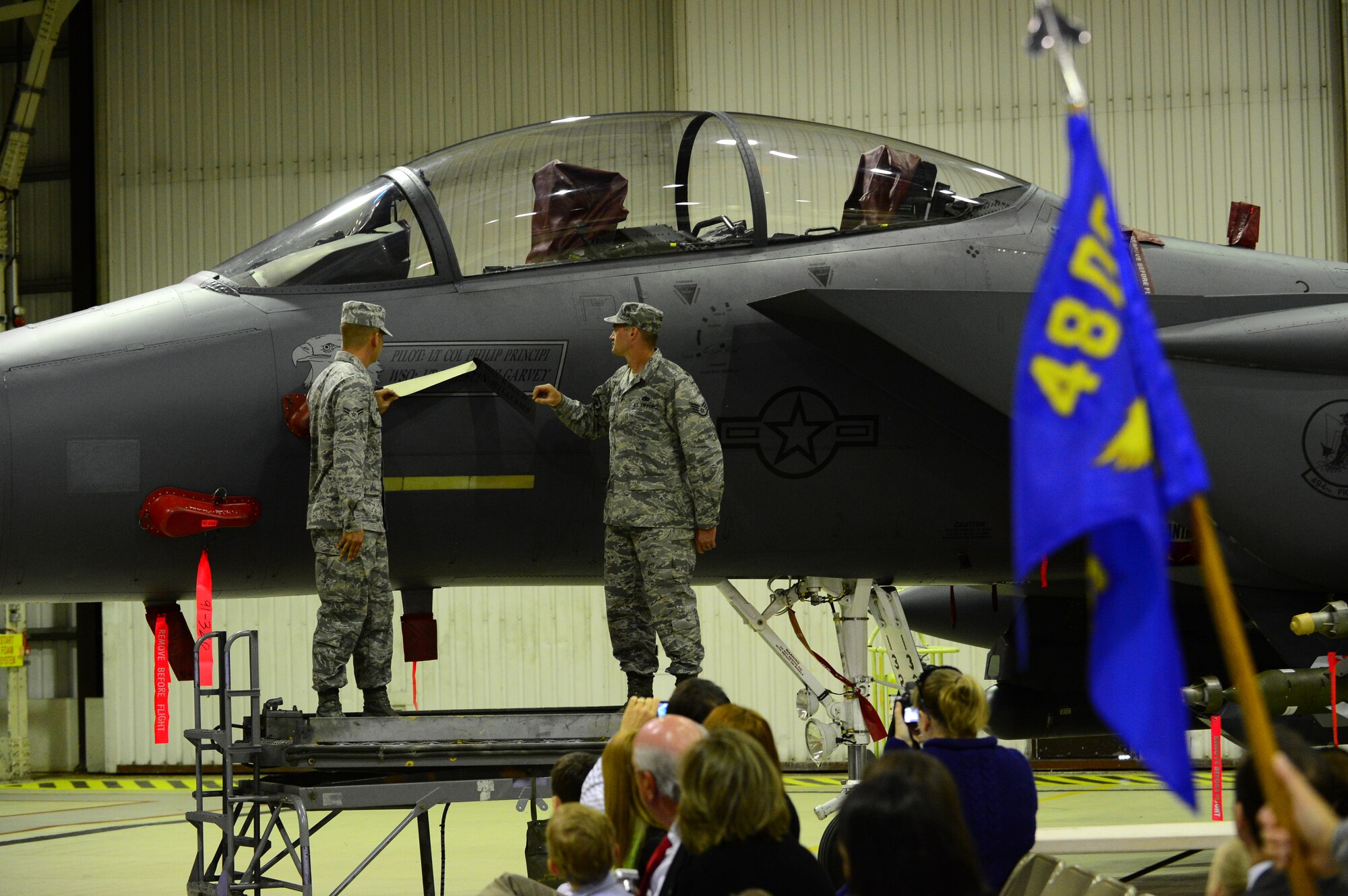 ROYAL AIR FORCE LAKENHEATH, England – Airman 1st Class Paul Swanson, (left) and Sgt. Veryl Kirkpatrick, 494th Aircraft Maintenance Unit dedicated crew chiefs, unveil the re-named squadron flagship during the 494th Fighter Squadron change of command June 6, 2013. Flagships are dedicated aircraft with the squadron commander and dedicated crew chief's names painted near the cockpit. (U.S. Air Force photo by Airman 1st Class Dana J. Butler)