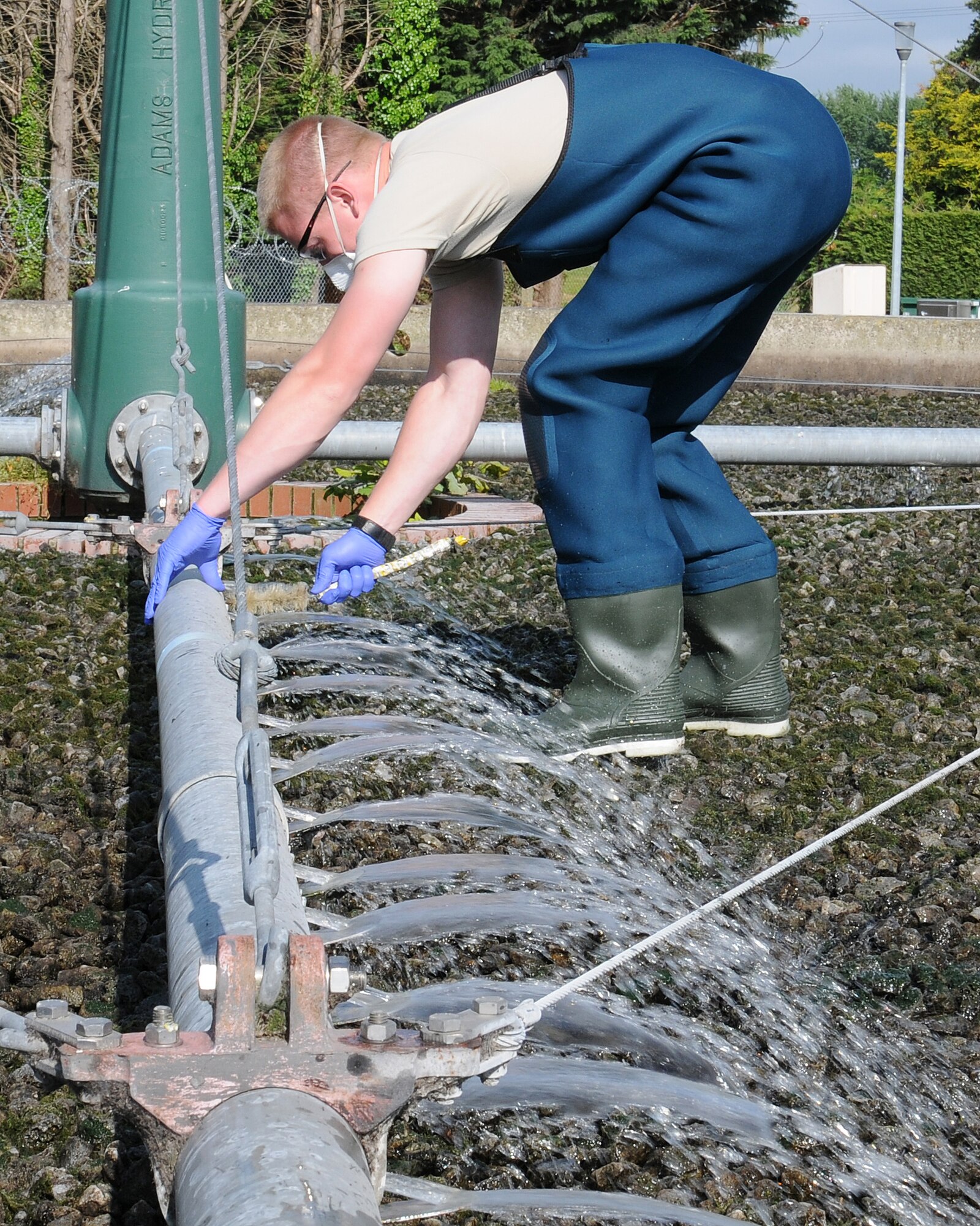 Senior Airman Andrew Burdette, 100th Civil Engineer Squadron Water and Fuels Maintenance journeyman from Victorville, Calif., flushes trickling filter arms June 6, 2013, at RAF Mildenhall, England. Water plant personnel showed Chief Master Sgt. Tracy Jones, 100th Air Refueling Wing command chief, how they take care of business as part of a “dirty jobs” program. (U.S. Air Force photo by Gina Randall/Released)