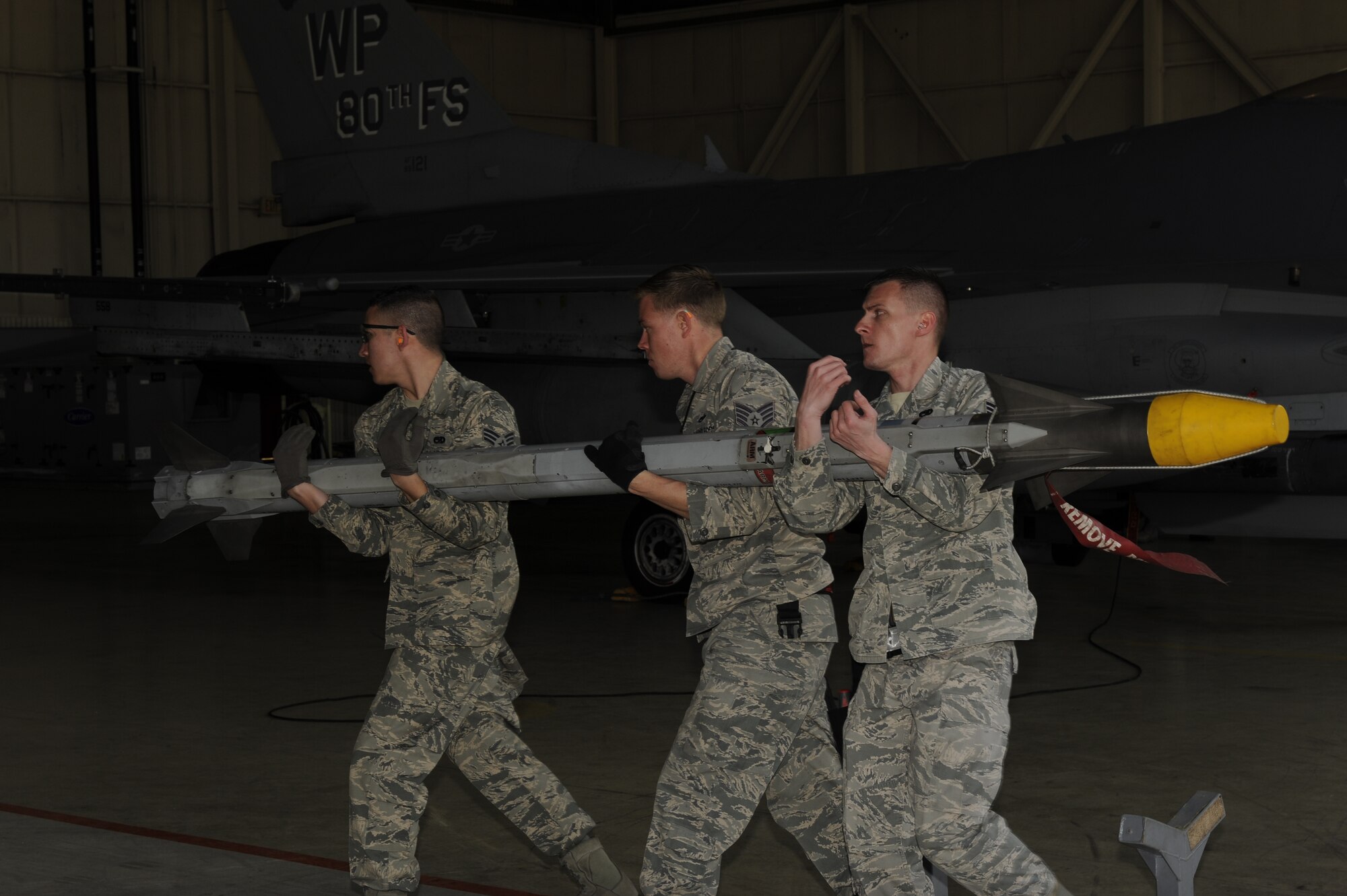 Senior Airman Daniel Repreza, left, Staff Sgt. Christopher Alteri, middle, and Senior Airman Andrew Rapp, 4th Expeditionary Aircraft Maintenance Unit, Hill Air Force Base, Utah carry a AIM 9X Sidewinder to an F-16 Fighting Falcon during a weapons loading competition at Kunsan Air Base, Republic of Korea, March 29, 2013. The 4th EAMU load crew started with 2,000 points and the Airmen were graded on several separate events. Scores from a 100-point written test, members dress and appearance and a composite tool kit inspection (all tools were present and properly marked,) were tracked, and points were added or taken away.  (U.S. Air Force photo by Senior Airman Marcus Morris/Released)