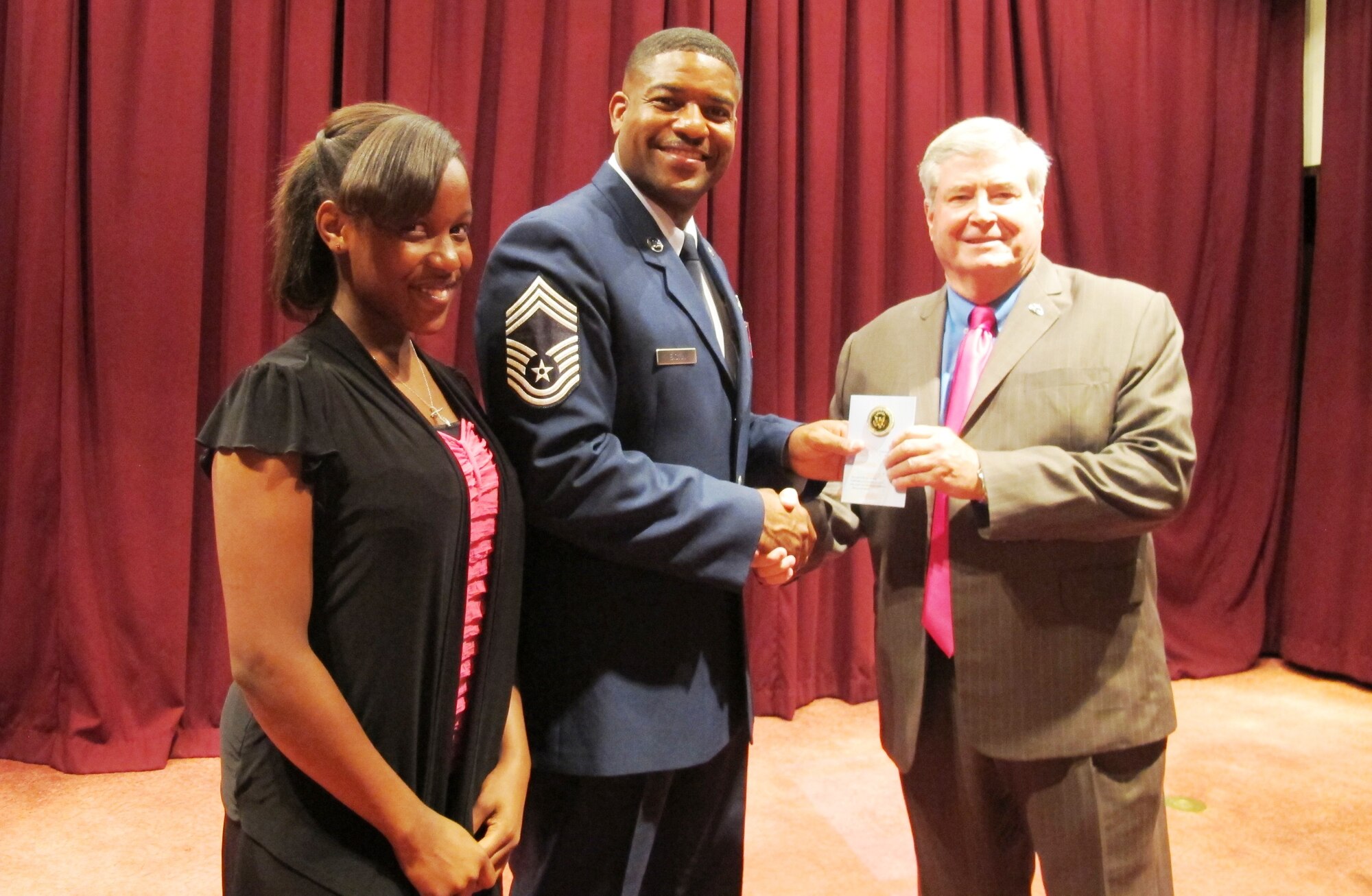 U.S. Air Force Chief Master Sgt. Phillip Easton, 18th Mission Support Group superintendent, and his daughter are recognized by Dr. Thomas Hawks, University of Phoenix Asia Pacific Military Campus director, at a "Team Dad" event at the Kadena Officers Club on Kadena Air Base, Japan, May 29, 2013. Easton helped distribute awards to children who were recognized for their outstanding essays written for the Team Dad contest. The essays were written by military students who live on Okinawa and attend Department of Defense Dependents Schools. The essays served as a tribute to their fathers and the important role they play in their lives. (Courtesy photo by Dr. Scott Goldberg)