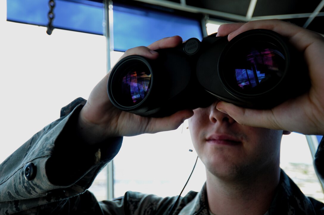 Senior Airman Michael-Paul Kendall, 36th Operations Support Squadron air traffic controller, looks through binoculars to ensure landing gear is down prior to an aircraft landing May 30, 2013, on Andersen Air Force Base, Guam. The Andersen Air Traffic Control Tower stands 168 feet and four inches tall to overlook the two active runways. (U.S. Air Force photo by Airman 1st Class Emily Bradley/Released)

