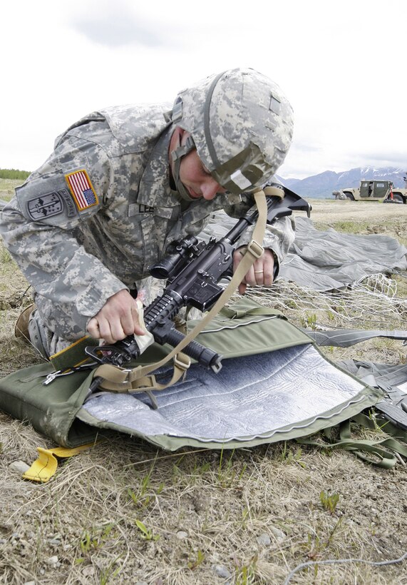 Army Staff Sgt. Otis Lee removes protective wrapping from his M4 carbine after a successful jump onto Malamute Drop Zone during Operation Spartan Reach on Joint Base Elmendorf-Richardson, Alaska, June 5, 2013. 