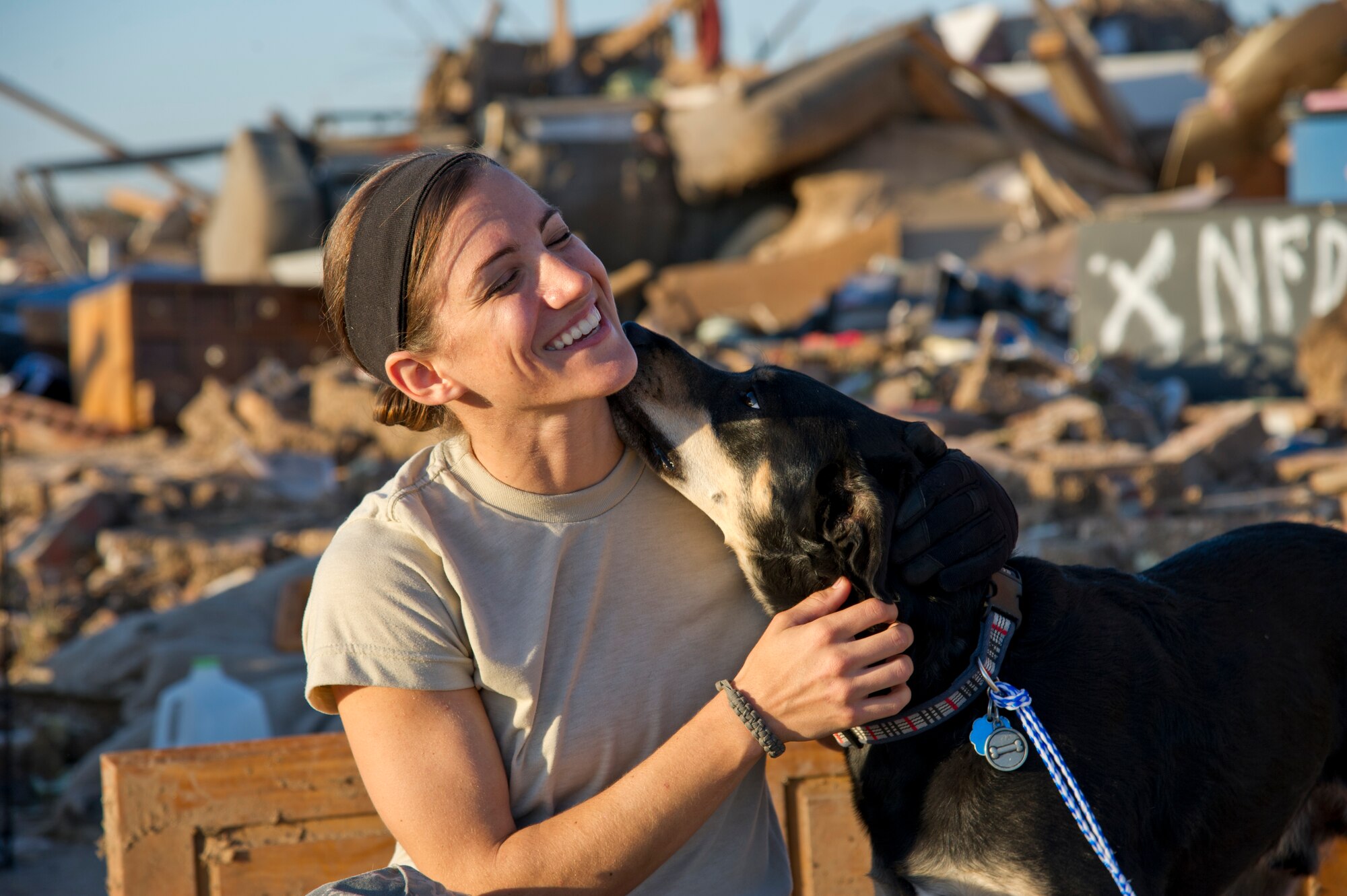 U.S. Air Force Staff Sgt. Caroline Hayworth, 4th Combat Camera Squadron, receives a friendly lick from a thankful dog expressing his excitement after pulling him from the remains of a home three days after a tornado completely destroyed his owners house, Okla., May 22, 2013. The 2 mile wide tornado demolished hundreds of houses and took lives, May 20, 2013. (Photo by Mike Meinhardt/Released)