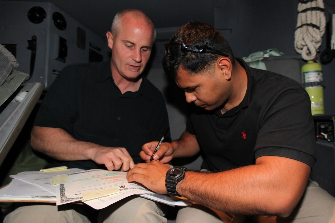 Sgt. Jeison Mendoza, Special-Purpose Marine Air-Ground Task Force Africa mortarman from Palmira, Colombia, verifies his information with John Lafferty, U.S. Citizenship and Immigration Services district director, in the cockpit of a KC-130J Super Hercules in Tripoli, Libya, June 4, 2013. Mendoza took the oath of allegiance and became a U.S. citizen while deployed with Special-Purpose MAGTF Africa and is currently in Libya providing additional security to U.S. Embassy Tripoli.