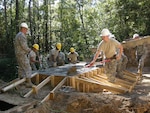 Now that six yards of concrete is in the form, National Guardsmen work together to spread and level it.