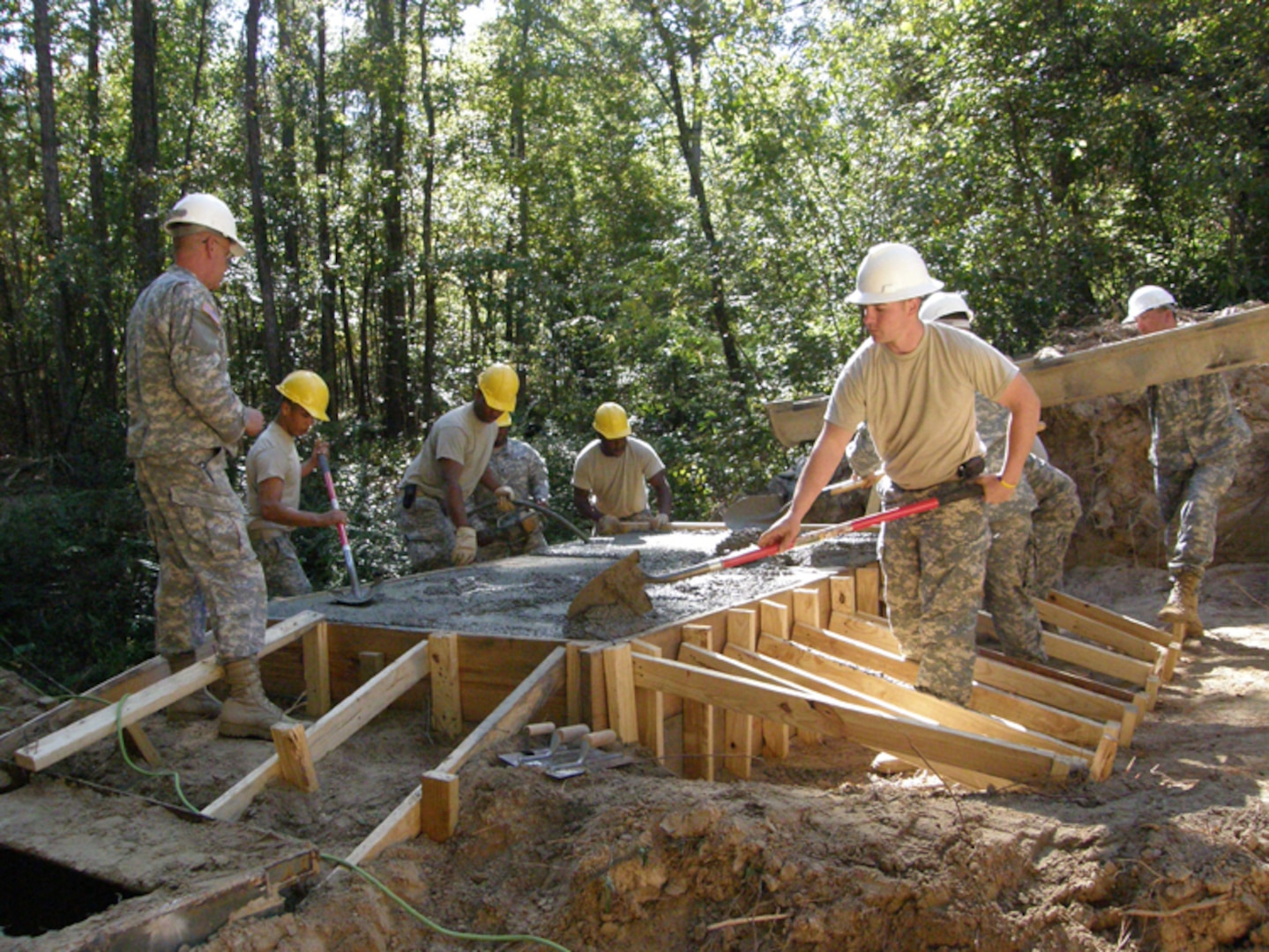 Now that six yards of concrete is in the form, National Guardsmen work together to spread and level it.