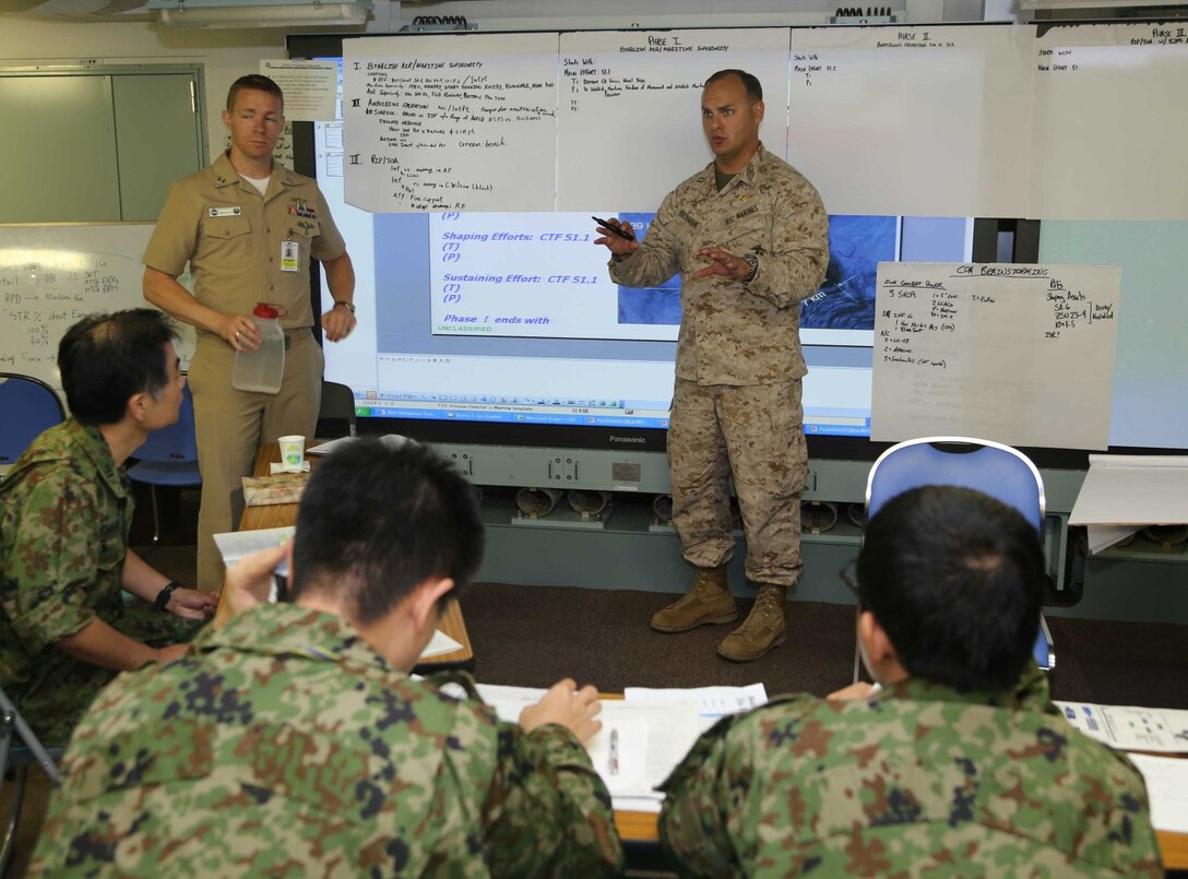 Capt. Philipp Buckhahn, 11th Marine Expeditionary Unit assistant air officer, talks with members of the Japanese Self Defense Force about amphibious operations during a planning exercise on board the Japanese ship Hyuga at Naval Base San Diego June 6.  The planning exericse gave Marines and sailors a chance share how U.S. ground components and maritime components work together to conduct amphibious operations.  This training is part of Exercise Dawn Blitz, which is scenario-driven exercise that refocuses Navy and Marine Corps and coalition forces in their ability to conduct complex ambibious operations.