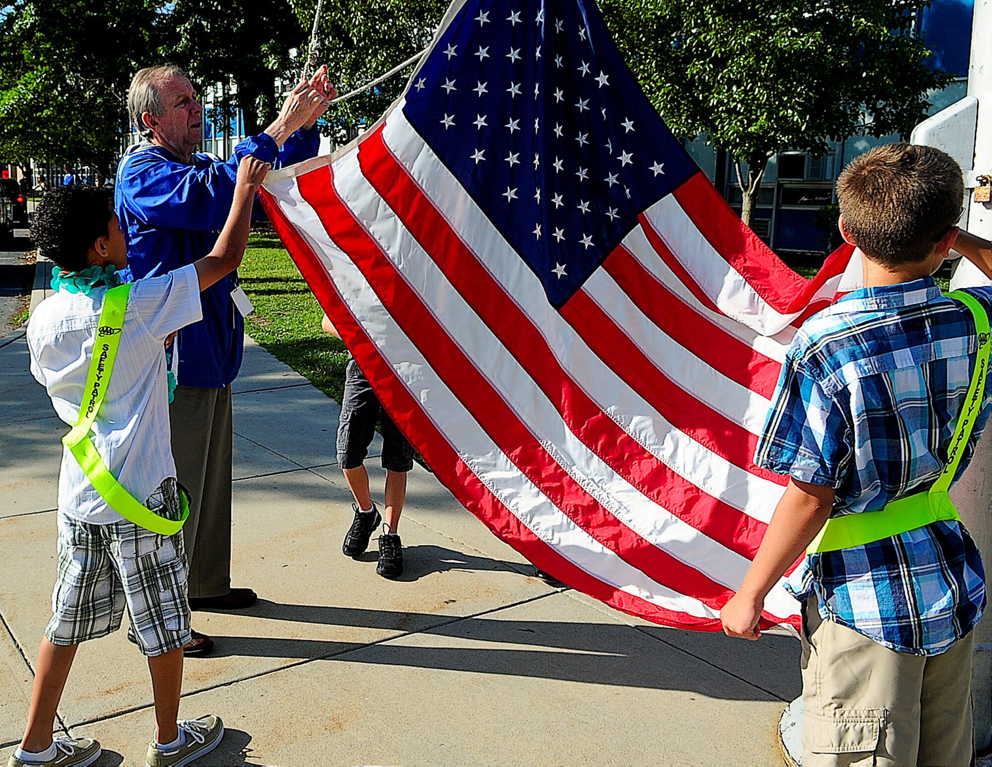 Jay Darcey, a retired Air Force chief master sergeant, helps children from Welch Elementary raise the flag June 5, 2013, on Dover Air Force Base, Del. Darcey is retiring from the school as the base security liaison. (U.S. Air Force photo/Airman 1st Class Ashlin Federick)