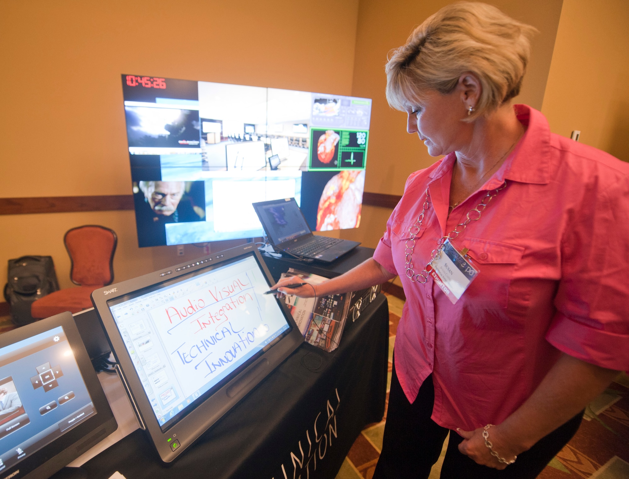 Susan Caine, project development planner, demonstrates how to work a SMART Podium Touch Screen during a technology exposition at the Soundside Club on Hurlburt Field, Fla., June 4, 2013. The conference provided a wide spectrum of technology with the convenience of a one-stop shop venue for interested Air Force members. (U.S. Air Force photo by Senior Airman Krystal M. Garrett)