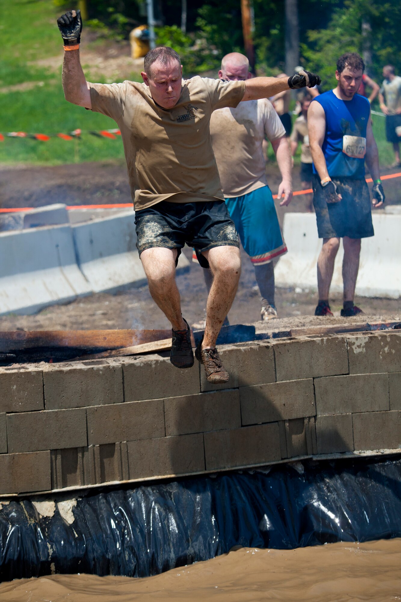 Col. Patrick Cobb, 102nd Intelligence Wing commander, jumps through fire into water in Gilford, N.H. on June 1, 2013. Twenty-eight members of the 102nd Intelligence Wing challenged themselves by completing the Boston Tough Mudder event. (National Guard photo by Staff Sgt. Jeremy Bowcock/Released)