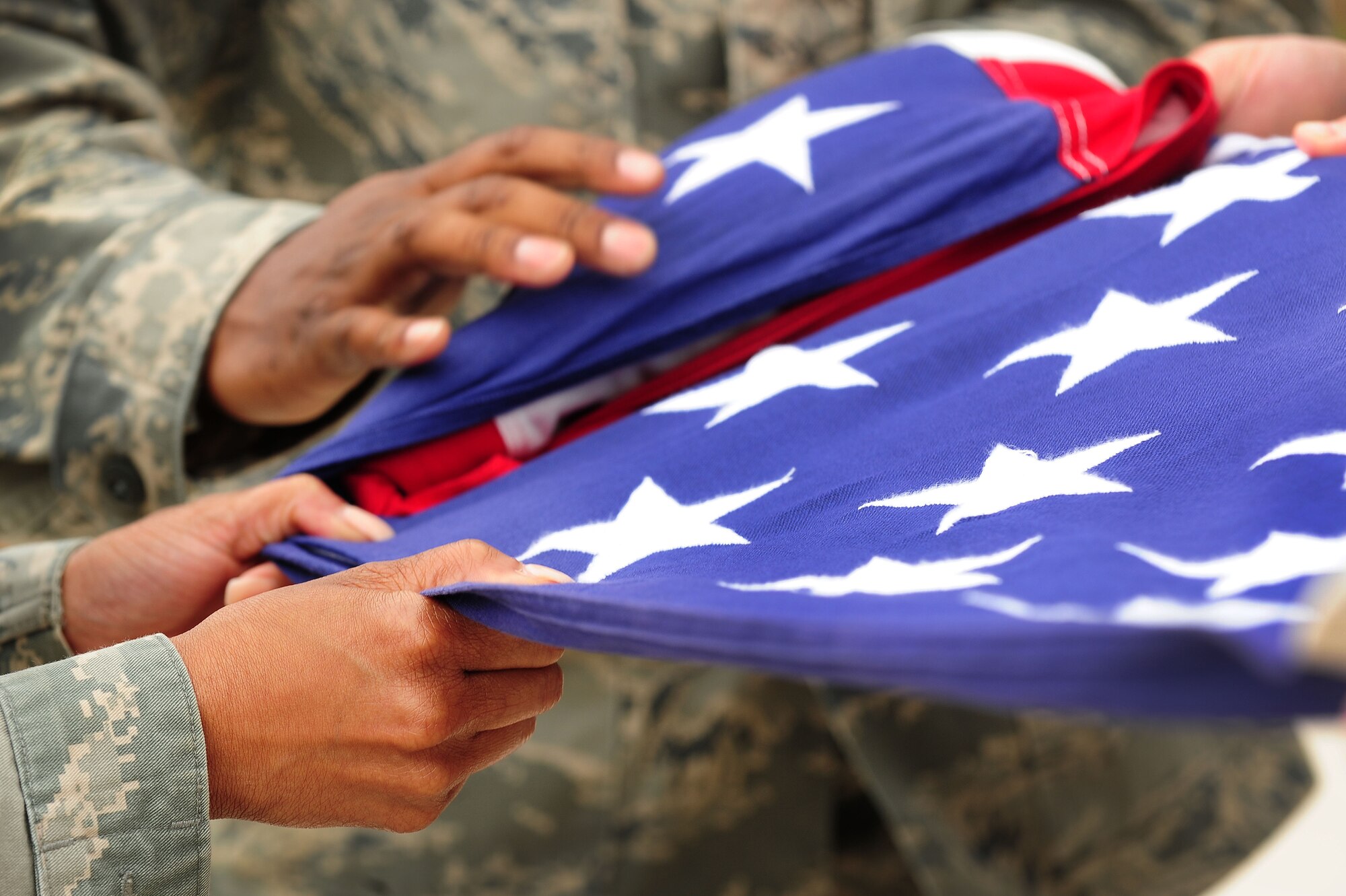 Headquarters Air Force District of Washington Staff Airmen fold the American flag during a retreat ceremony, June 6, 2013, at Joint Base Andrews, Md. The colors of the flag represent valor and bravery in the red stripes, purity and innocence in the white stars and stripes, and vigilance, perseverance, and justice in the blue field. (U.S. Air Force photo by Senior Airman Steele C. G. Britton)