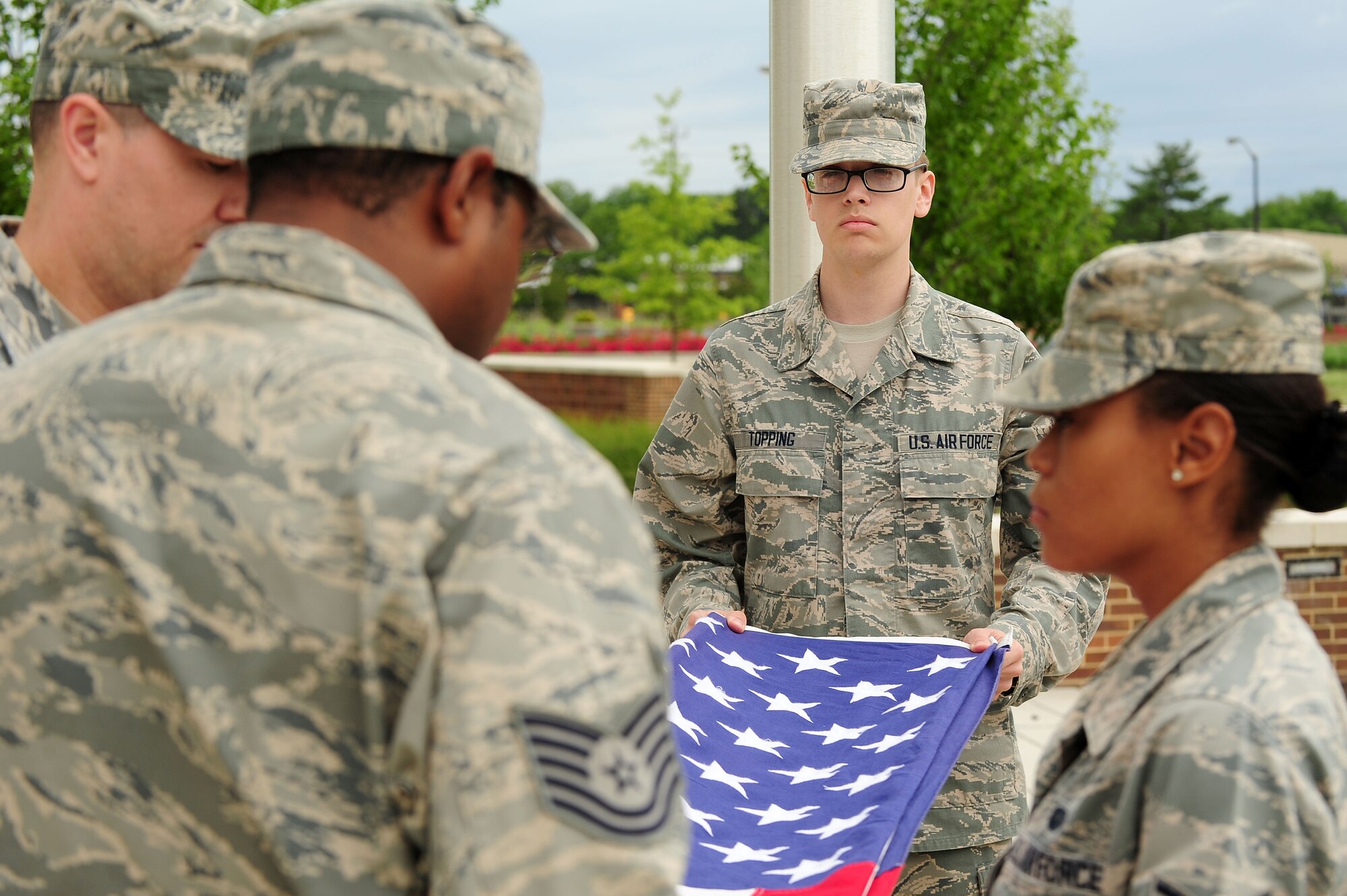Airman 1st Class Seth Topping and fellow Headquarters Air Force District of Washington Staff Airmen participate in a flag detail during a retreat ceremony, June 6, 2013, at Joint Base Andrews, Md. The 13-fold tradition honors those who serve and have served the United States both at home and abroad. (U.S. Air Force photo by Senior Airman Steele C. G. Britton)