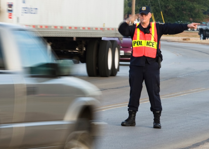 Officer Dave Walker, 7th Security Forces Squadron, directs traffic June 7, 2013, at Dyess Air Force Base, Texas. In order to operate a vehicle on Dyess Air Force Base, motorists must have a valid state drivers license, valid proof of insurance, valid military identification or base pass and a valid state registration and emissions test if required by their state. (U.S. Air Force photo by Airman 1st Class Peter Thompson/Released)