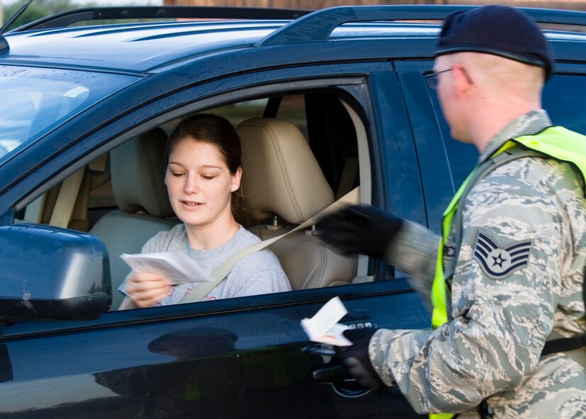 U.S. Air Force Airman 1st Class April Thompson, 7th Bomb Wing judge advocate, hands her proof of insurance and license to Staff Sgt. Thomas Dooley, 7th Security Forces Squadron, during a Roadway Blitz June 7, 2013, at Dyess Air Force Base, Texas. The 7th SFS processed approximately 1,200 vehicles during the two and a half hour Roadway Blitz, which was organized to assure on-base motorists are complying with state and base vehicle regulations. (U.S. Air Force photo by Airman 1st Class Peter Thompson/Released)