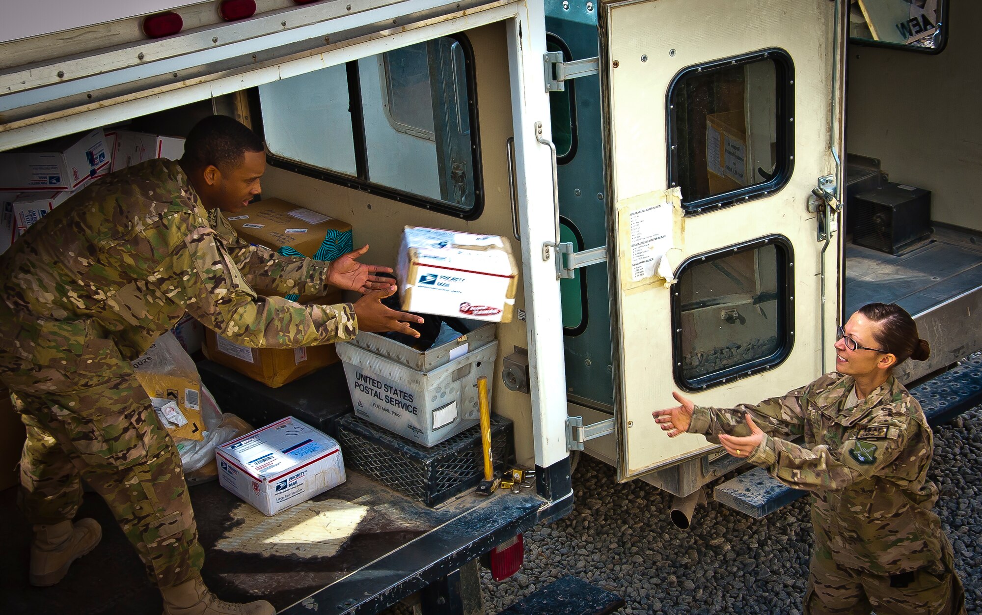 U.S. Air Force Senior Airman Ken Wise, 451st Air Expeditionary Wing mail custodian, tosses a package to U.S. Air Force Staff Sgt. Hollie Darling, 361st Expeditionary Reconnaissance Squadron and mail crew volunteer, at Kandahar Airfield, Afghanistan, May 10, 2013. Darling is one of many volunteers from different squadrons within the wing that help gather, sort and distribute mail. The mail crew handles about 50,000 pounds of mail weekly. (U.S. Air Force/photo Senior Airman Scott Saldukas)
