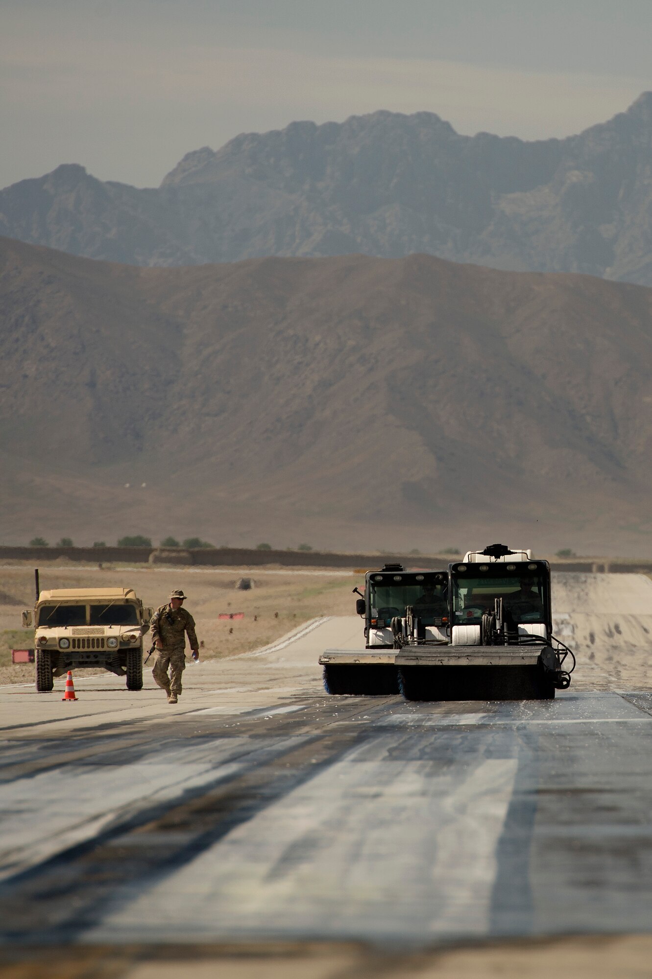 Tech. Sgt. Mike Carnahan, 577th Expeditionary Prime Base Engineer Emergency Force Squadron, noncommissioned officer in charge of rubber removal, assists Tool Cat drivers with angle brush height adjustments used to agitate a water and chemical rubber removal process on a runway at Forward Operating Base Shank, Logar province, Afghanistan, June 4, 2013. Runway maintenance is a composite team built from many civil engineering backgrounds. Carnahan, hailing from Fort Worth, Texas, is a water utilities maintenance technician by trade. (U.S. Air Force photo/Master Sgt. Ben Bloker)