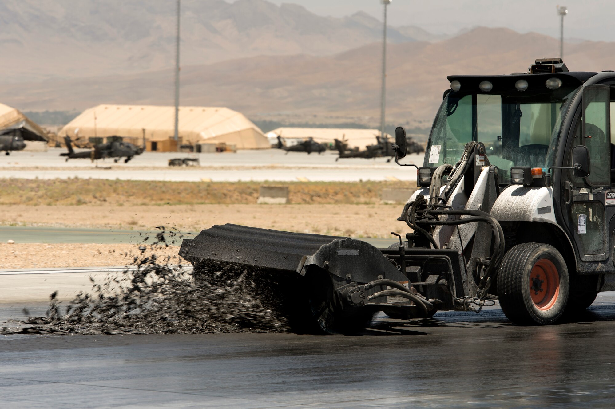 Blackened rubbery foam flies off an angle brush from a Tool Cat piloted by Senior Airman Jessie Rivera, 577th Expeditionary Prime Base Engineer Emergency Force Squadron, on a runway at Forward Operating Base Shank, Logar province, Afghanistan, June 5. Runway maintenance is a composite team built from many civil engineering backgrounds. Rivera, hailing from Denver, is an electrical power production technician by trade. (U.S. Air Force photo/Master Sgt. Ben Bloker)