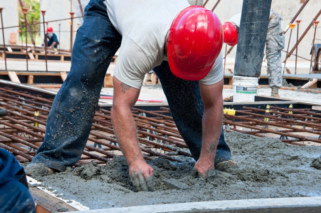 Tech Sgt. David Popp, 554th RED HORSE Squadron engineer, spreads concrete mix with his hands May 23, 2013, on Northwest Field, Guam. The 12,500 square foot facility will be used to store all of the electricians’ systems equipment and will be the ninth tilt-up building the engineers have constructed since they began using the method in 2008. (U.S. Air Force photo by Senior Airman Robert Hicks/Released) 

