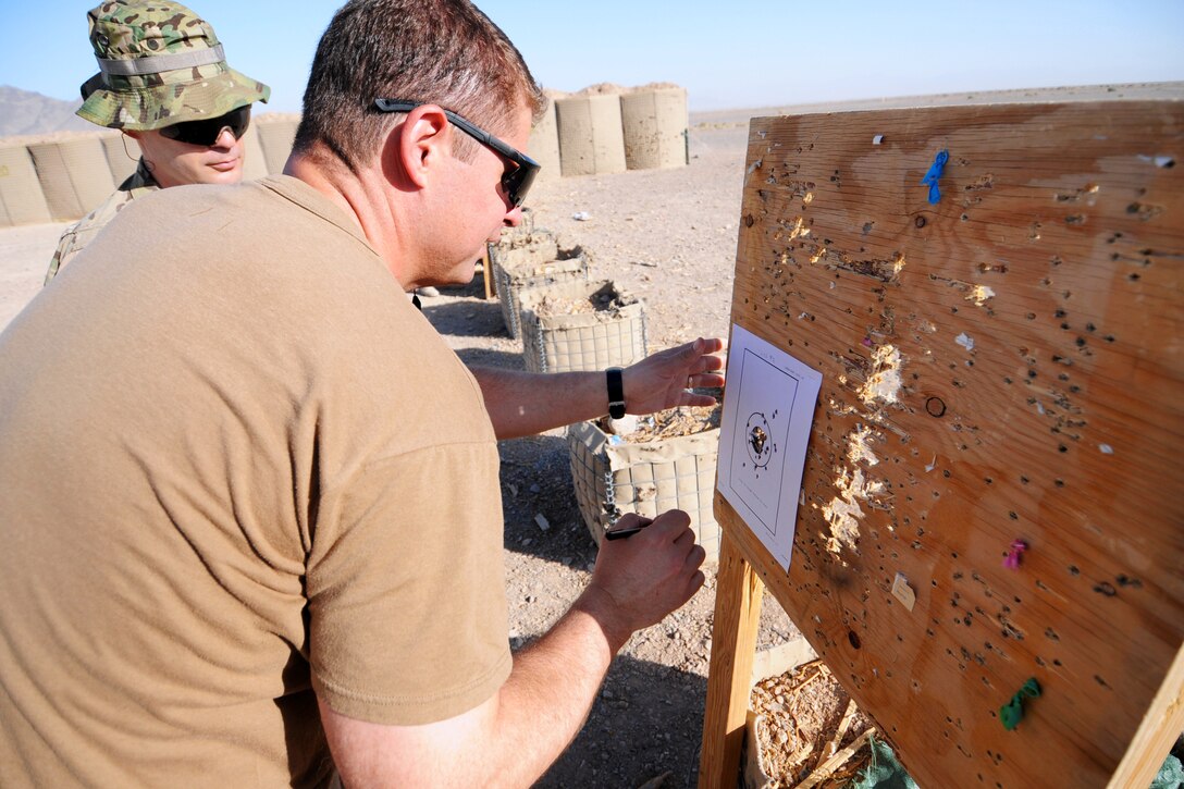 U.S. Navy Senior Chief Todd English, front, reviews a score card with U.S. Navy Petty Officer 2nd Class Sean Petty after completing a rifle qualification on Forward Operating Base Farah in Farah province, Afghanistan, June 8, 2013. English, a special warfare boat operator, and Petty, a logistics specialist, are assigned to Provincial Reconstruction Team Farah.