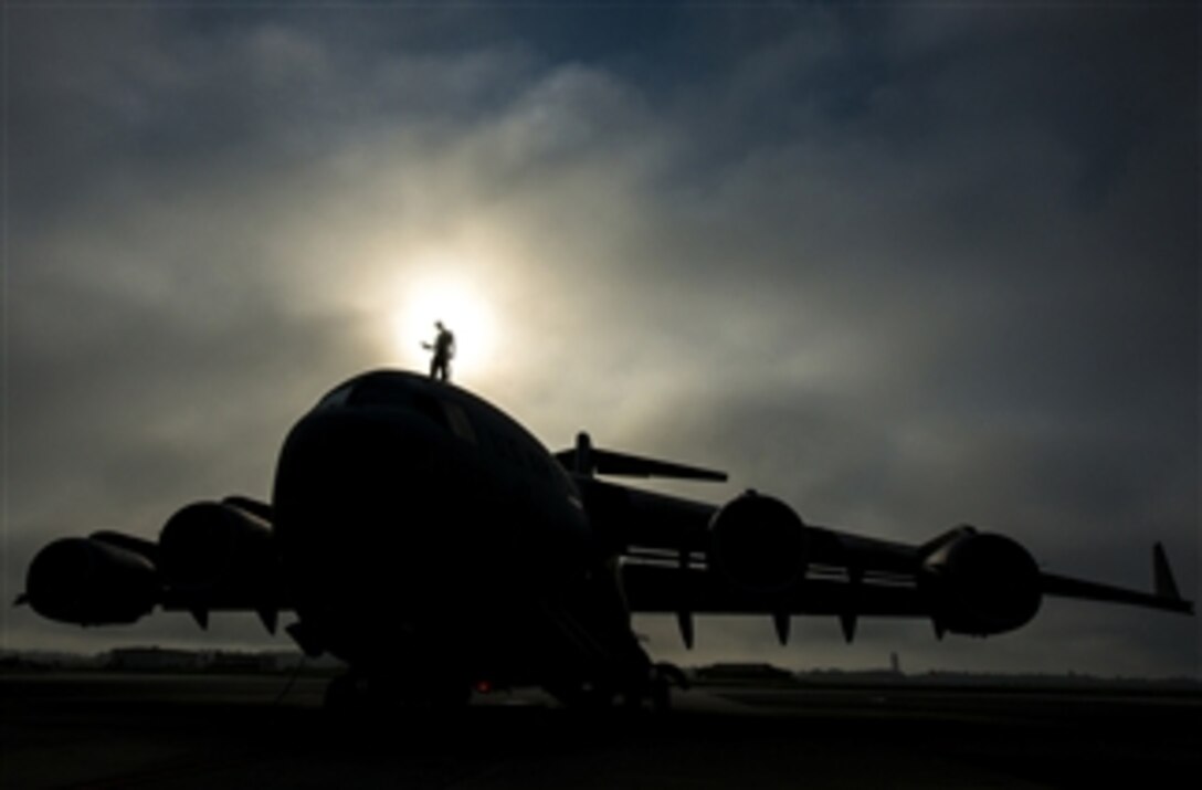 U.S. Air Force Tech. Sgt. Andrew Gravett walks along the top of a C-17 Globemaster III while wearing a safety harness as he does a routine maintenance check of the aircraft at Joint Base Charleston, S.C., on June 4, 2013.  Gravett is a crew chief assigned to the 437th Aircraft Maintenance Squadron.  