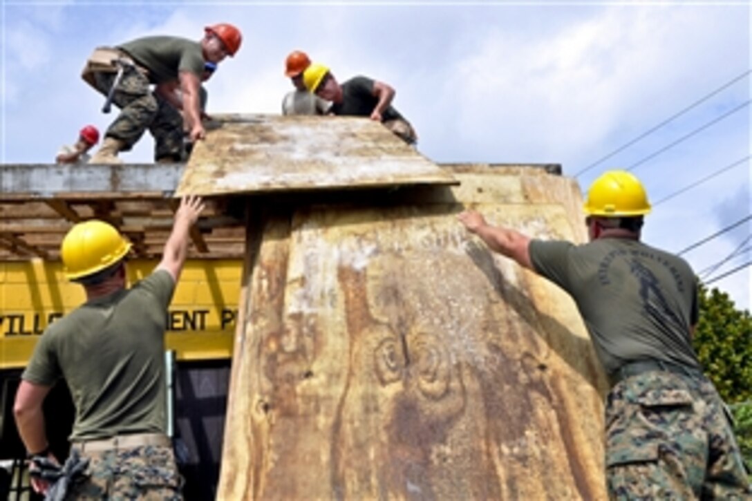 U.S. Marines and U.S airmen move roof decking to repair the leaky roof at a Hattieville school as part of New Horizons in Hattieville, Belize, June 4, 2013. The Marines are assigned to the Marine Wing support squadrons 471 and 472, and the airmen are assigned to the 823rd Red Horse Squadron. 