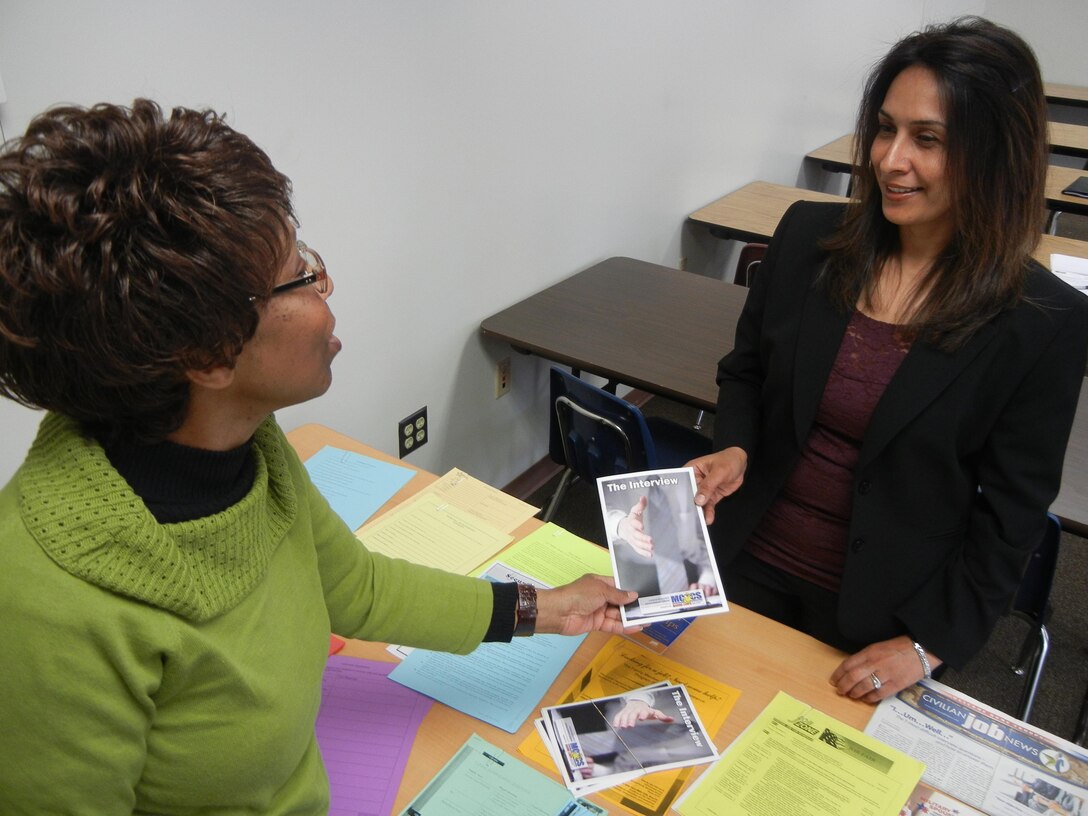 Barbara West, program coordinator for the Family Member Employment Assistance Program offers Kishwar Speir, a Marine spouse, literature on interviewing after the “‘Acing the Interview”’ workshop April 16, 2013, at the Voluntary Education Center aboard Marine Corps Base Quantico.                 