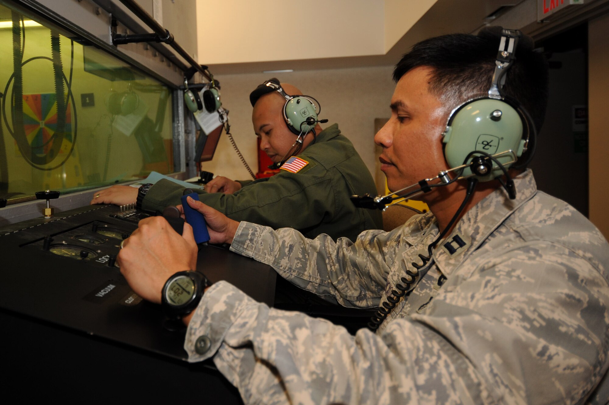U.S. Air Force Capt. Anthony Francisco, 18th Medical Group executive officer and aerospace and operational physiology flight officer in charge, prepares to "fly" the altitude chamber while U.S. Air Force Staff Sgt. Nazareth Oliver, 18th Aerospace Medicine Squadron aerospace and operational physiology flight NCO in charge of maintenance, briefs students within the chamber on Kadena Air Base, Japan, June 11, 2013. The altitude chamber is designed to simulate students flying to 25,000 feet in altitude and familiarize them with the symptoms associated with a lack of oxygen. (U.S. Air Force photo by Airman 1st Class Hailey R. Davis/Released)