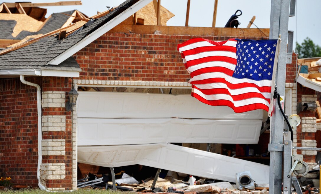 An American flag flies proudly despite the carnage that lies behind it. A house destroyed by the EF-5 (Enhanced Fujita Scale) tornado that tore through Moore, Okla. May 20.The tornado caused more than $2 billion in damages. (U.S. Air Force photo/Kimberly Goff /Released)