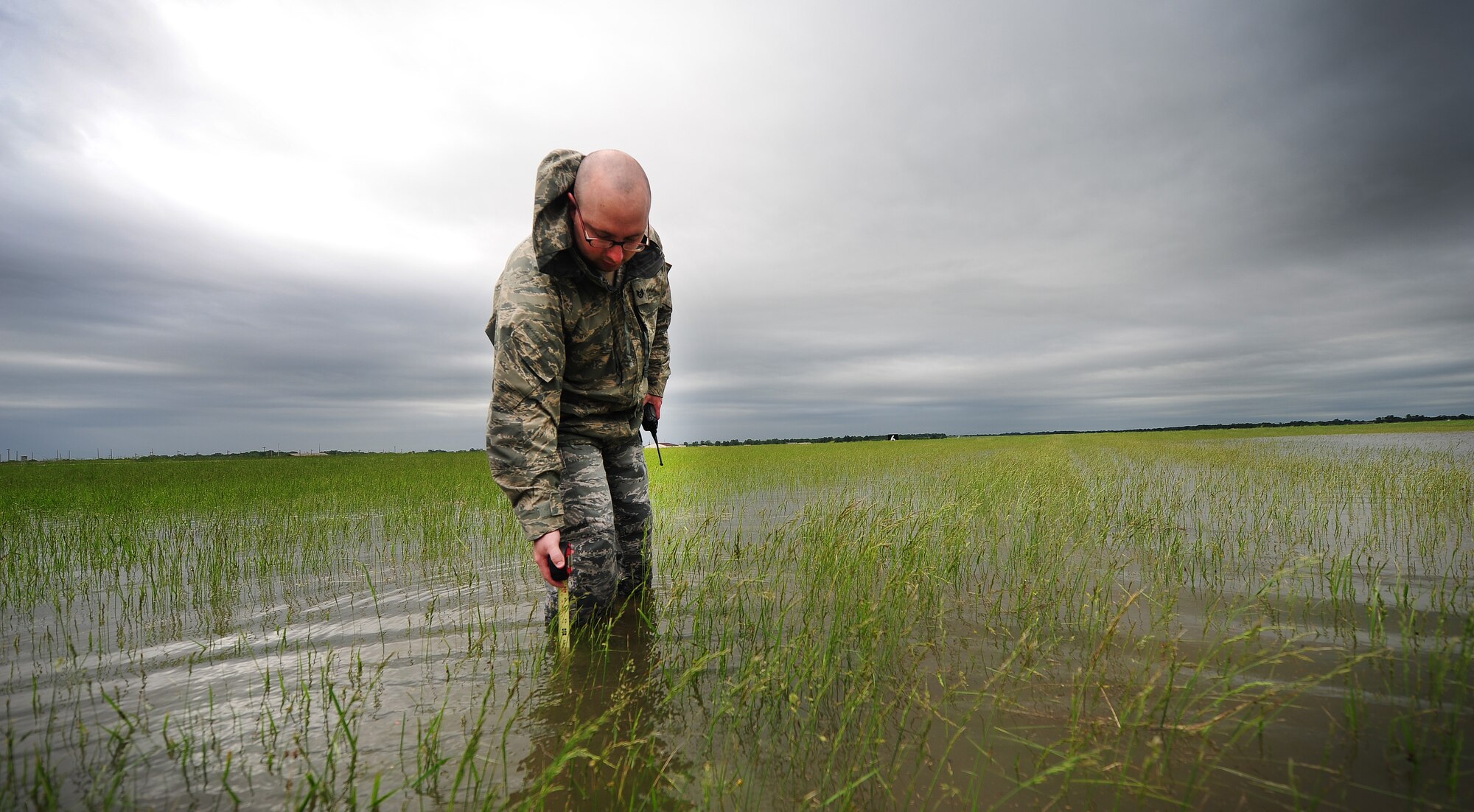 Staff Sgt. Timothy Cole, 509th Operations Support Squadron airfield management operations supervisor, conducts a rainwater assessment at Whiteman Air Force Base, Mo., May 31, 2013. The rainwater assessments are part of a daily inspection airfield managers complete at least 12 times a day. The safety of Whiteman's airfield depends on the expertise of airfield managers. (U.S. Air Force photo by Staff Sgt. Nick Wilson/Released)